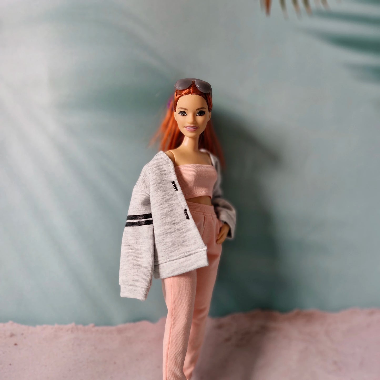 Barbie doll wearing a gray oversized jacket layered over a pink tube top and pink sweatpants.