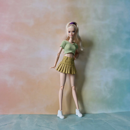 Barbie doll in a green top and skirt against a gradient background