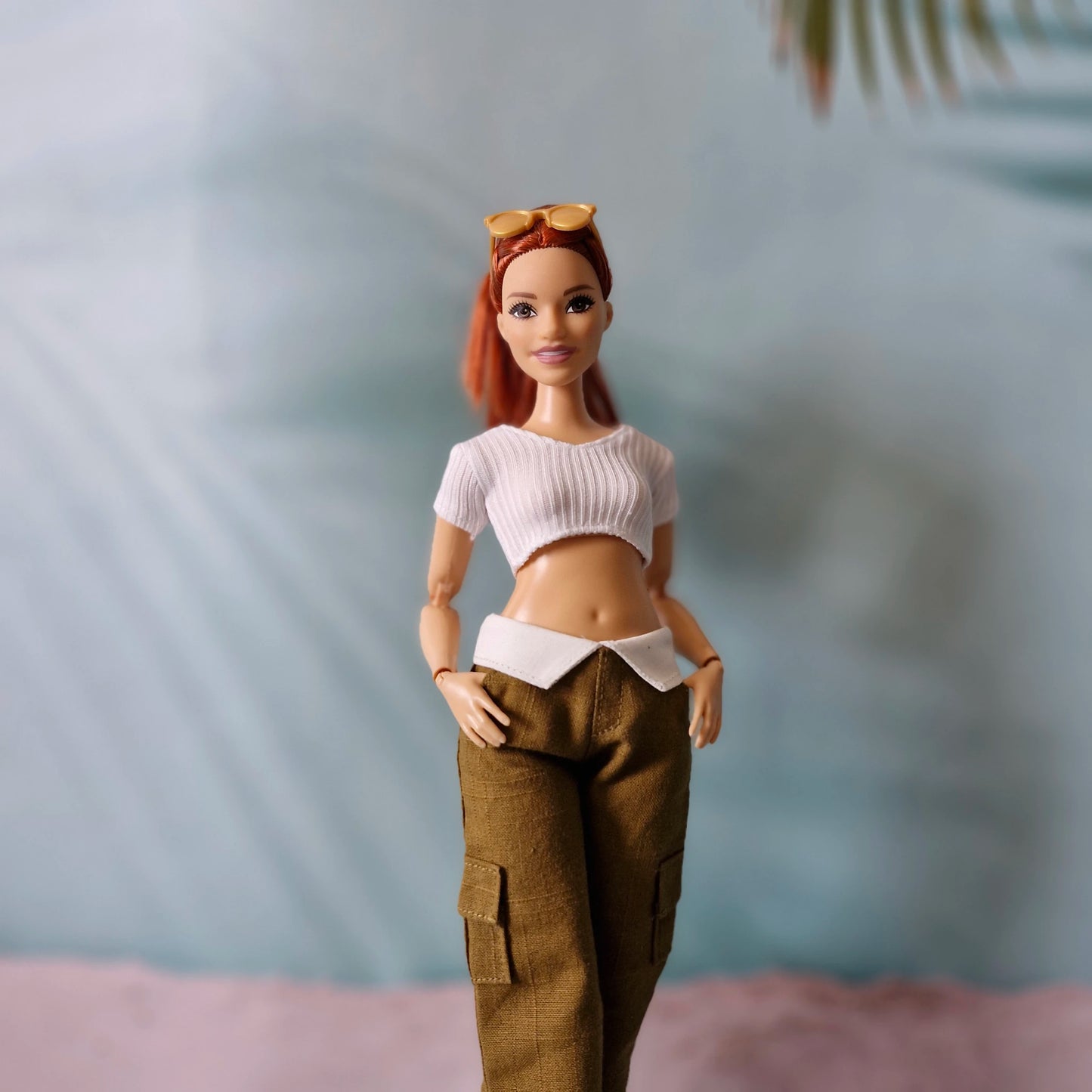 Barbie doll with red hair and a white top with a brown background
