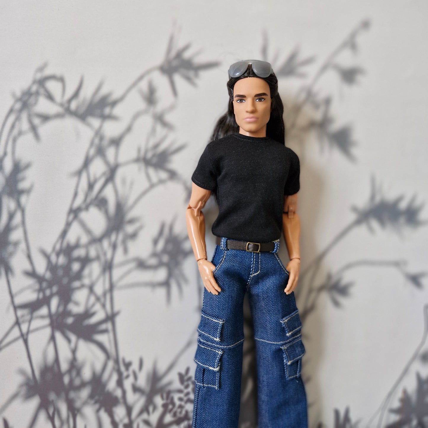 Ken doll posing in everyday casual fashion featuring a black tee and blue jeans