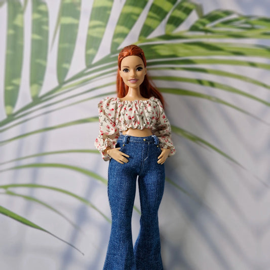 Close-up of a stylish doll wearing a pink floral crop top and high-waisted dark denim jeans for Curvy Barbie.