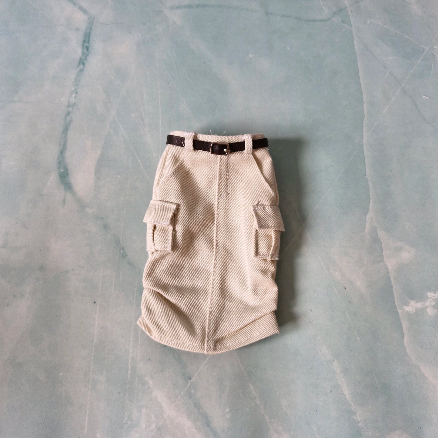 Beige cargo-style dog coat on a textured gray surface