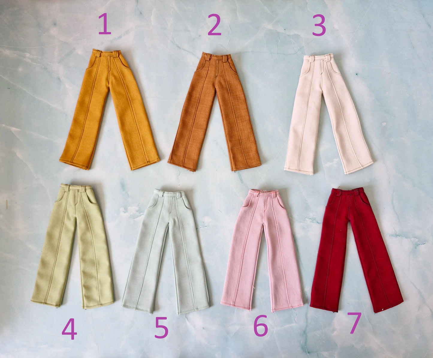 Flat lay of seven different colors of wide-leg Barbie doll pants numbered one through seven