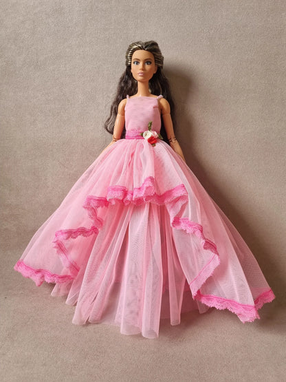 Fashion doll wearing romantic pink tulle gown with cascading ruffled layers and dark pink lace edging.