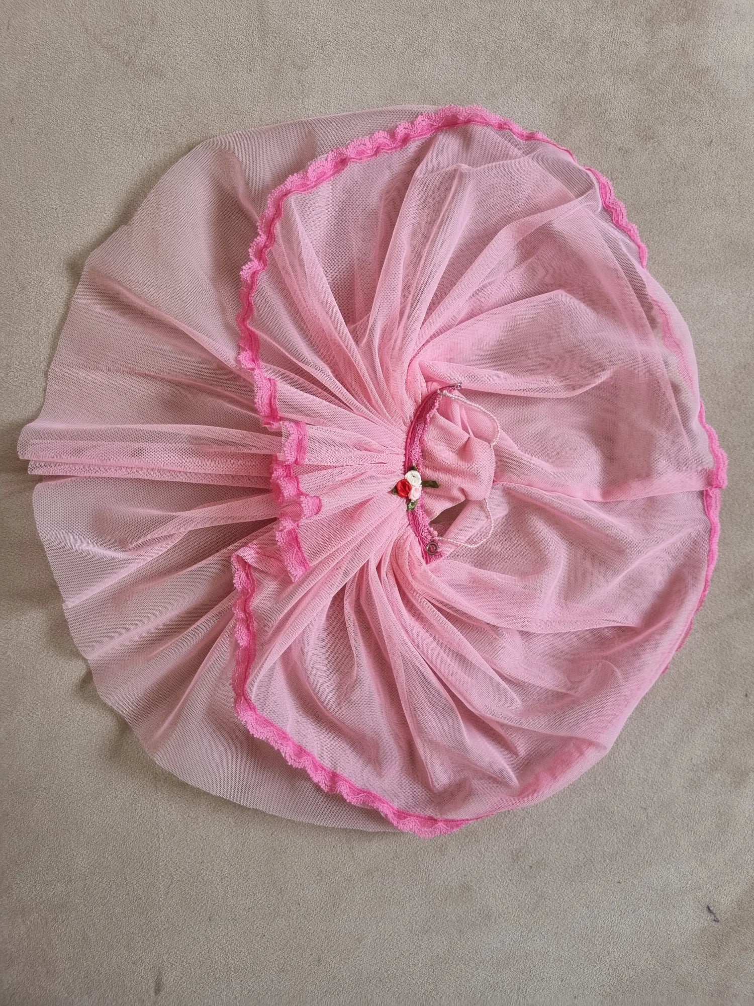 Pink tulle Barbie ball gown laid flat, showing full circular skirt, layers, lace trim, and floral waist detail from above.