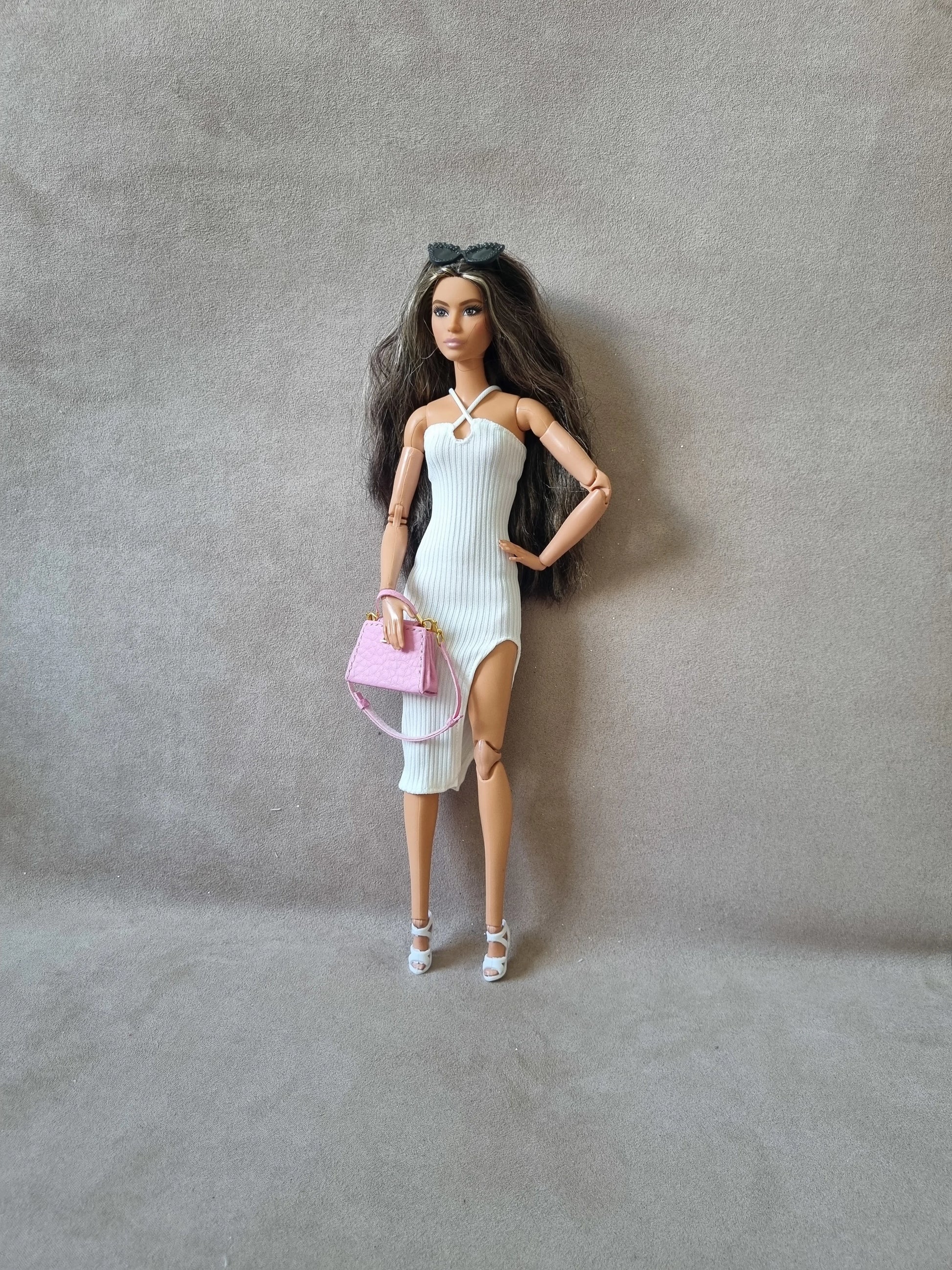 Barbie doll wearing white ribbed midi dress without sleeves, holding pink purse, sunglasses on head, white heels.