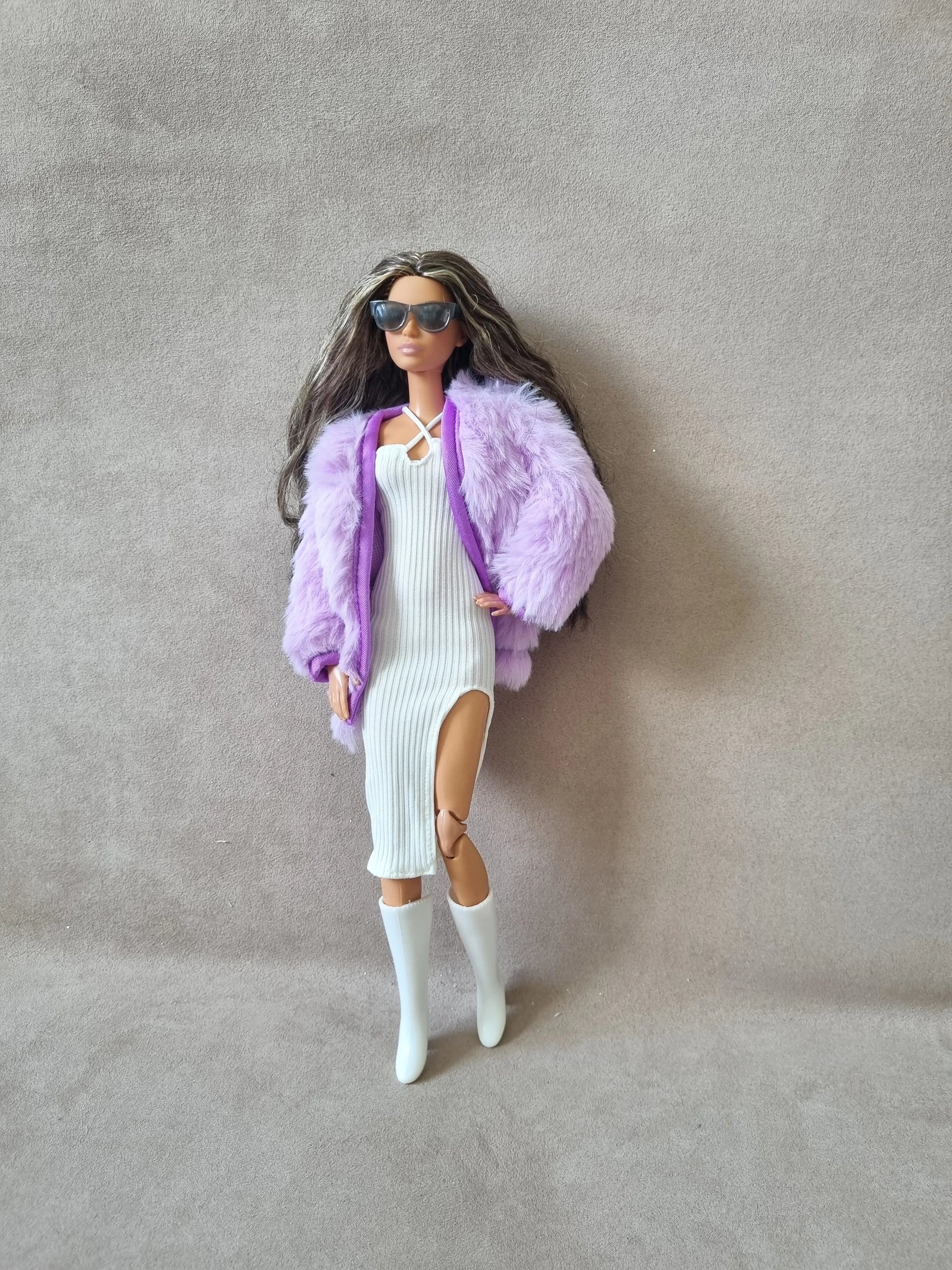 Fashion doll models glamorous look: white ribbed dress with slit, lavender faux fur coat, sunglasses, and white boots.
