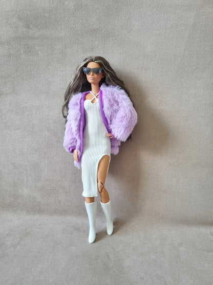 Fashion doll models glamorous look: white ribbed dress with slit, lavender faux fur coat, sunglasses, and white boots.