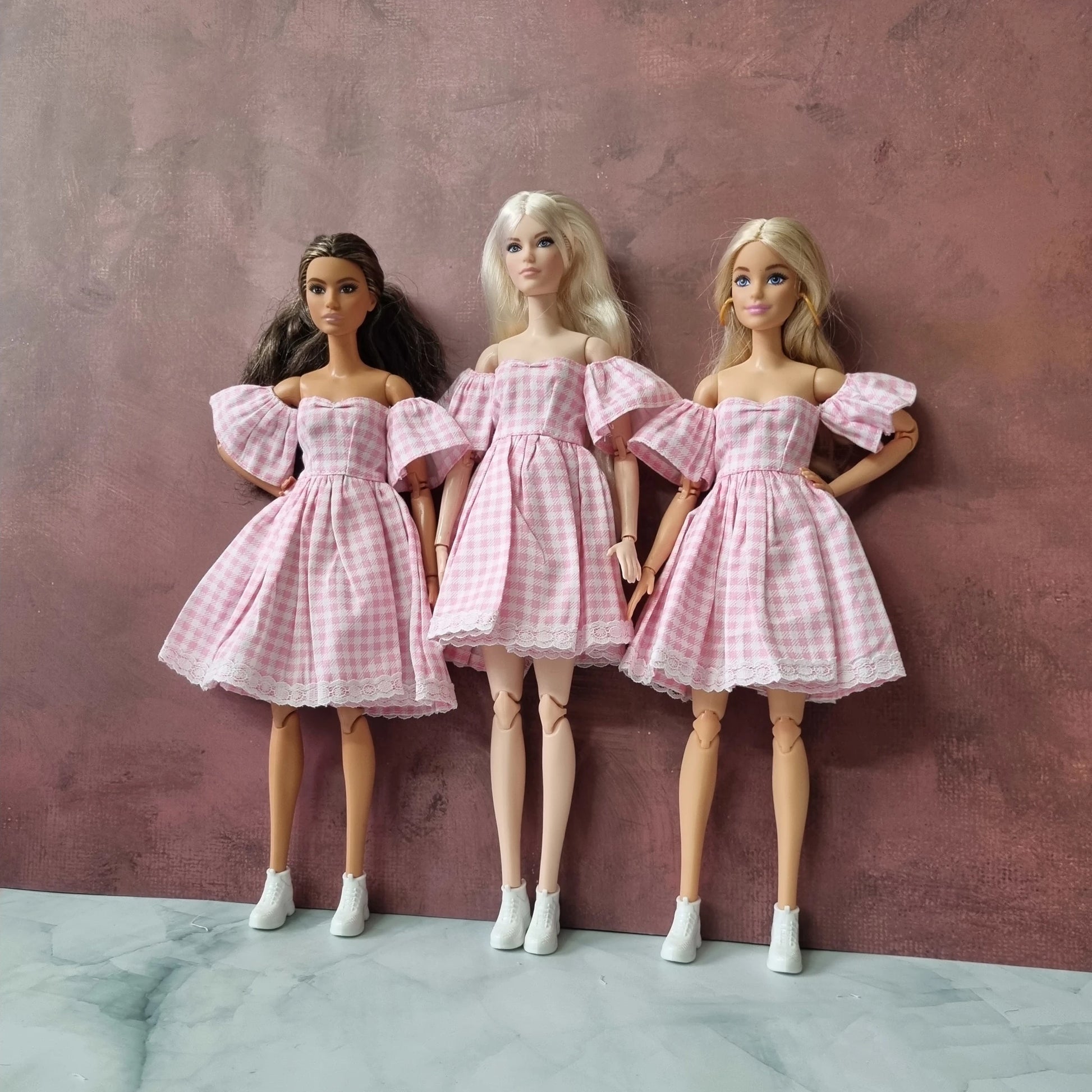 Barbie dolls dressed in retro pink gingham dresses posing together