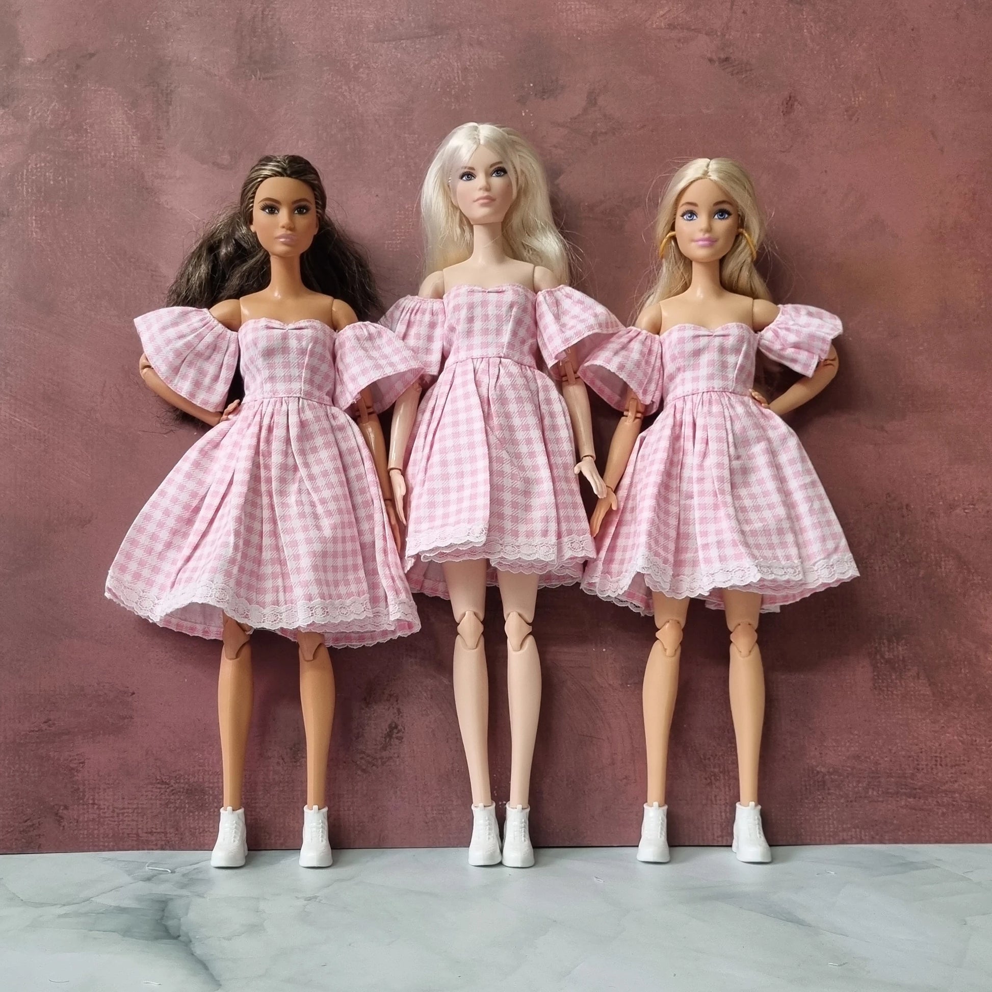 Barbie dolls wearing pink gingham off-shoulder dresses with lace trim