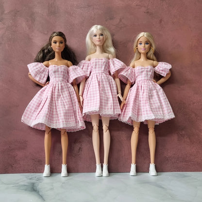 Barbie dolls wearing pink gingham off-shoulder dresses with lace trim
