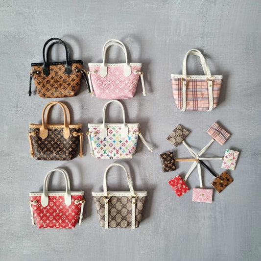 Flat lay of 7 different designer-inspired miniature tote bags for dolls with matching pouches.