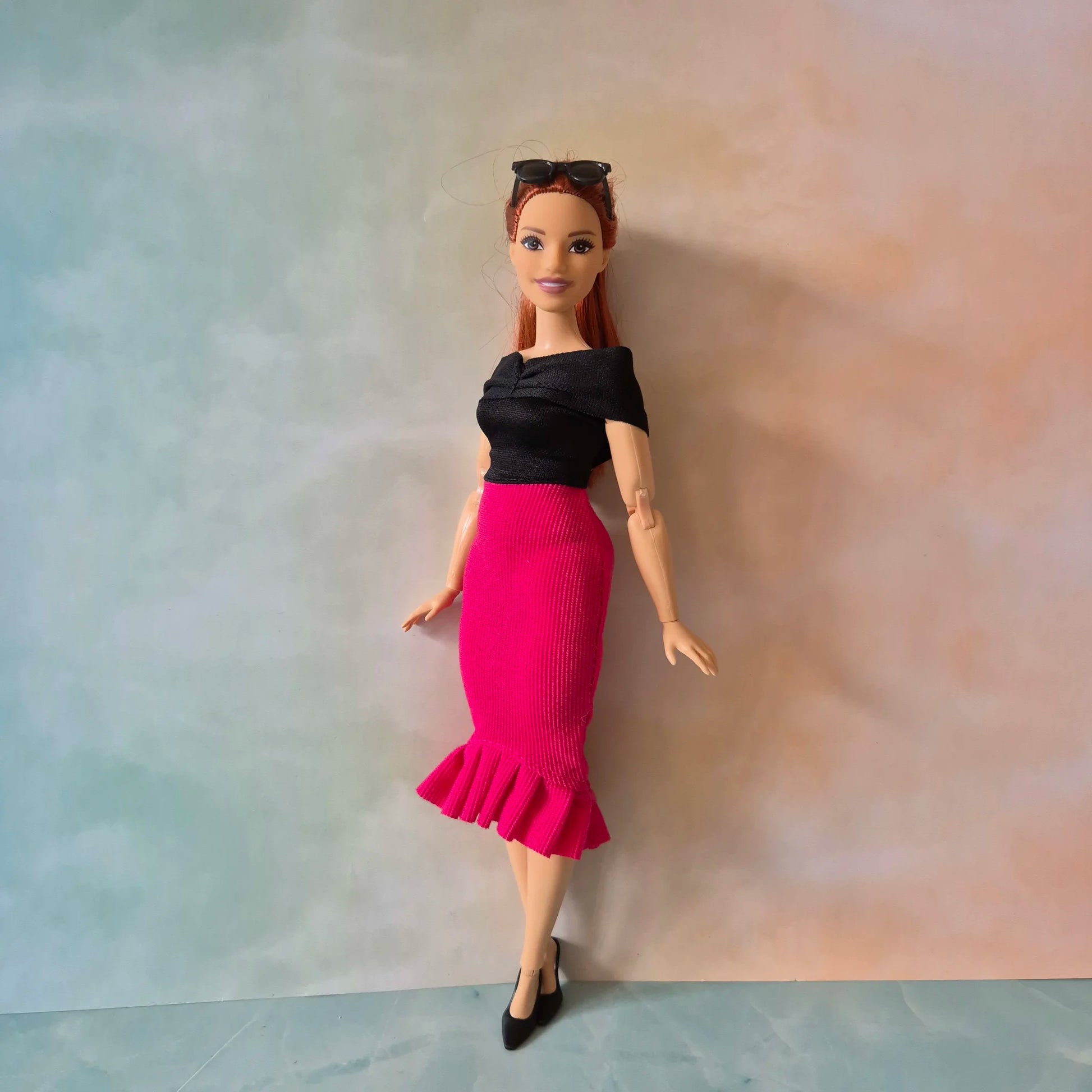 Front view of Barbie doll wearing sophisticated black top and hot pink mermaid skirt outfit.