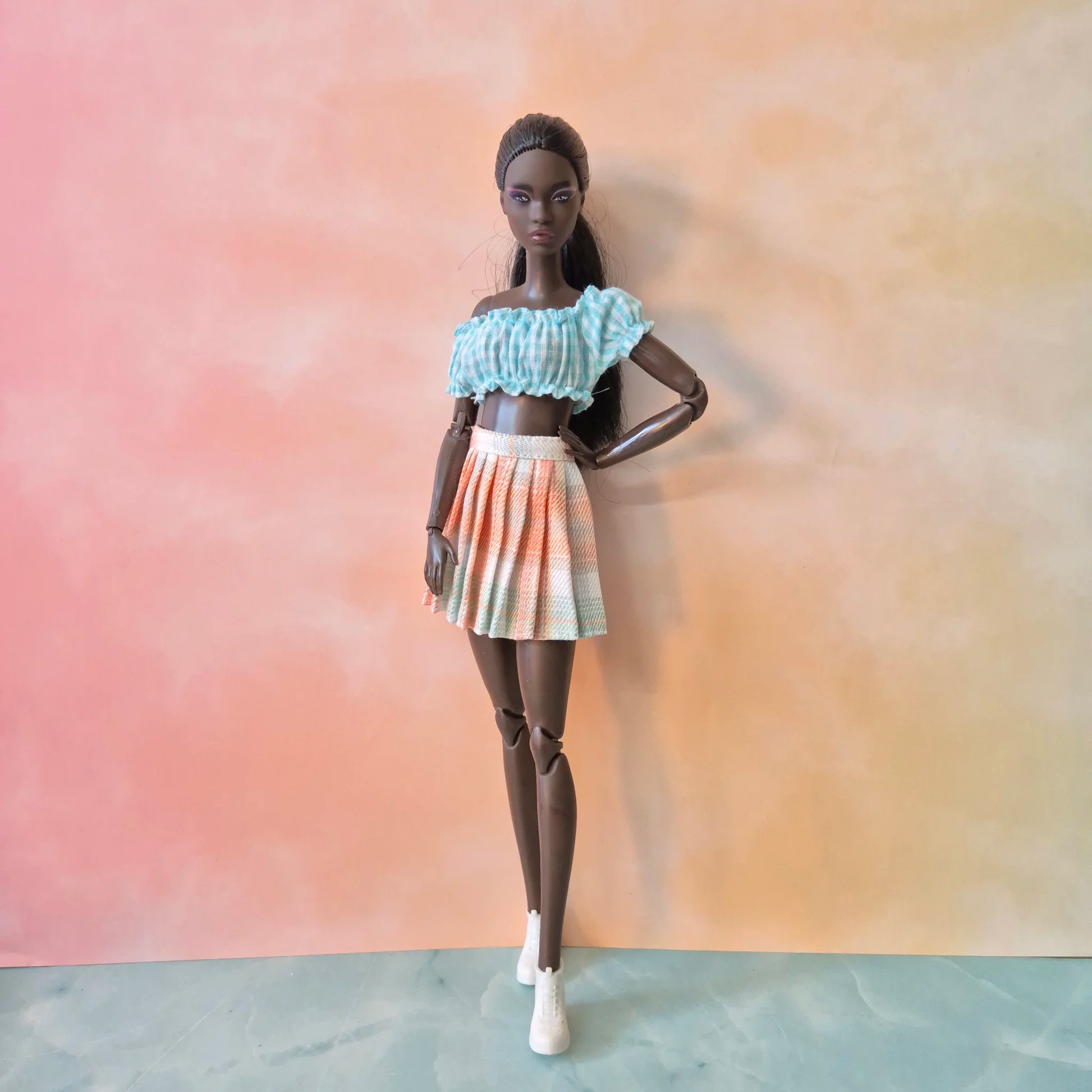 Dark-skinned Barbie doll with black hair in blue gingham off-shoulder top and peach plaid skirt.