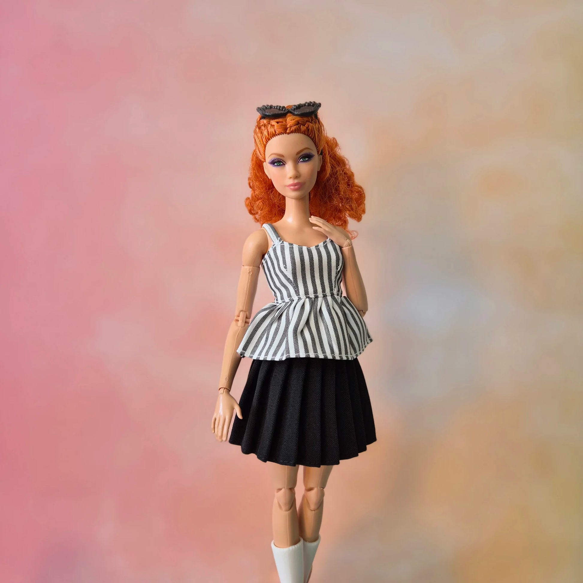 Red-haired Barbie doll in black & white striped peplum top and black pleated skirt.