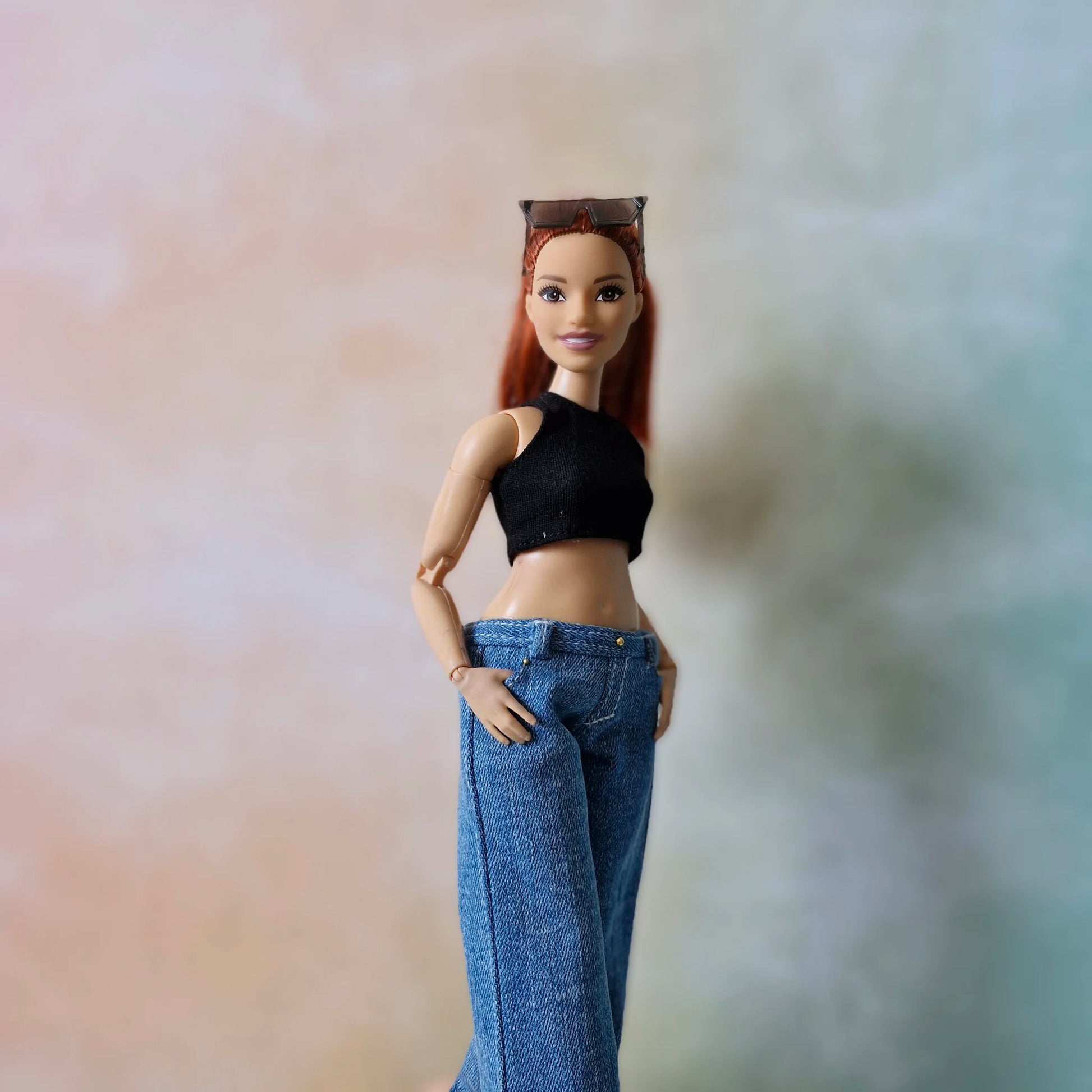 Redhead Curvy Barbie doll models wide-leg jeans and black top with hands in pockets