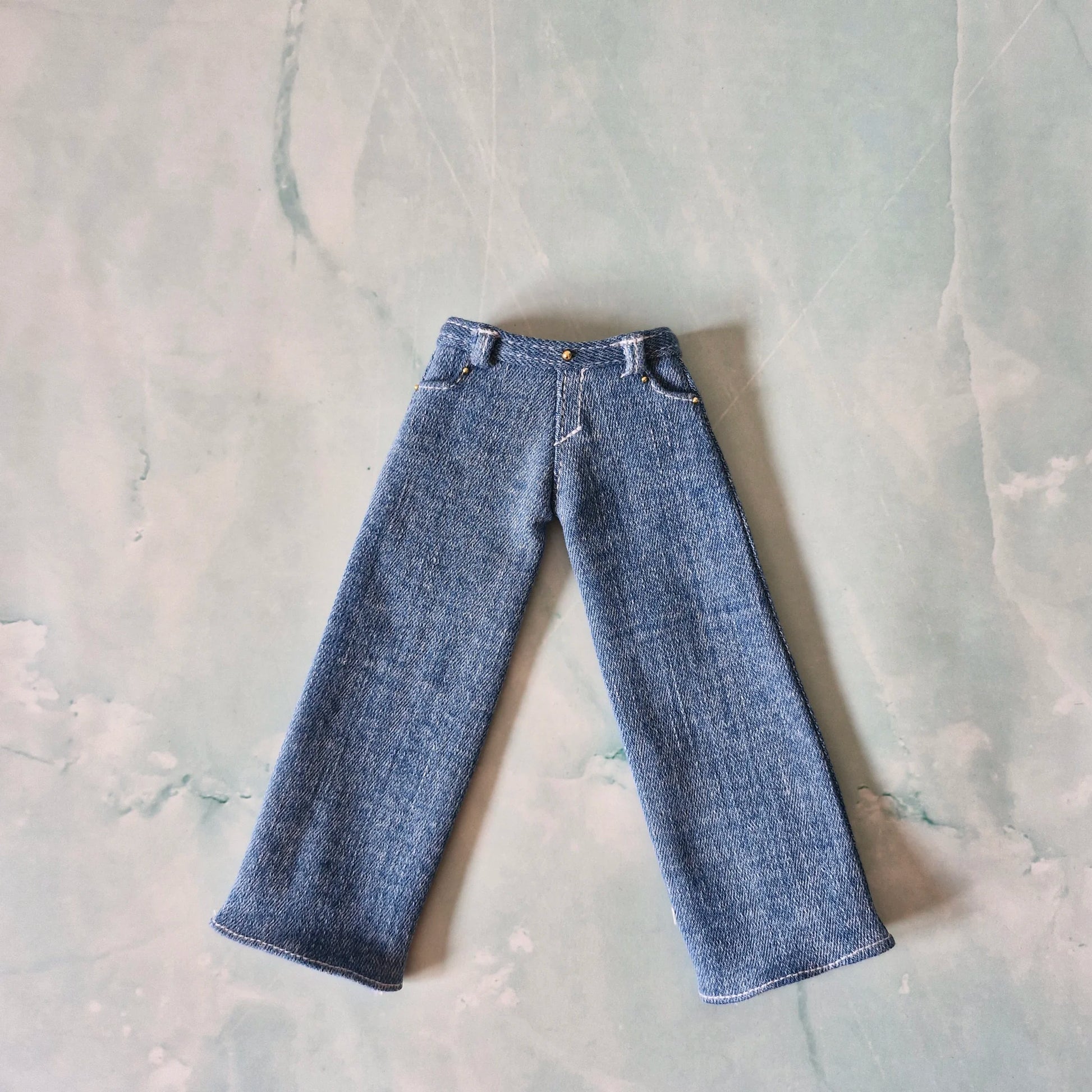 Flat lay view of wide-leg blue denim jeans for Curvy Barbie dolls with pocket details