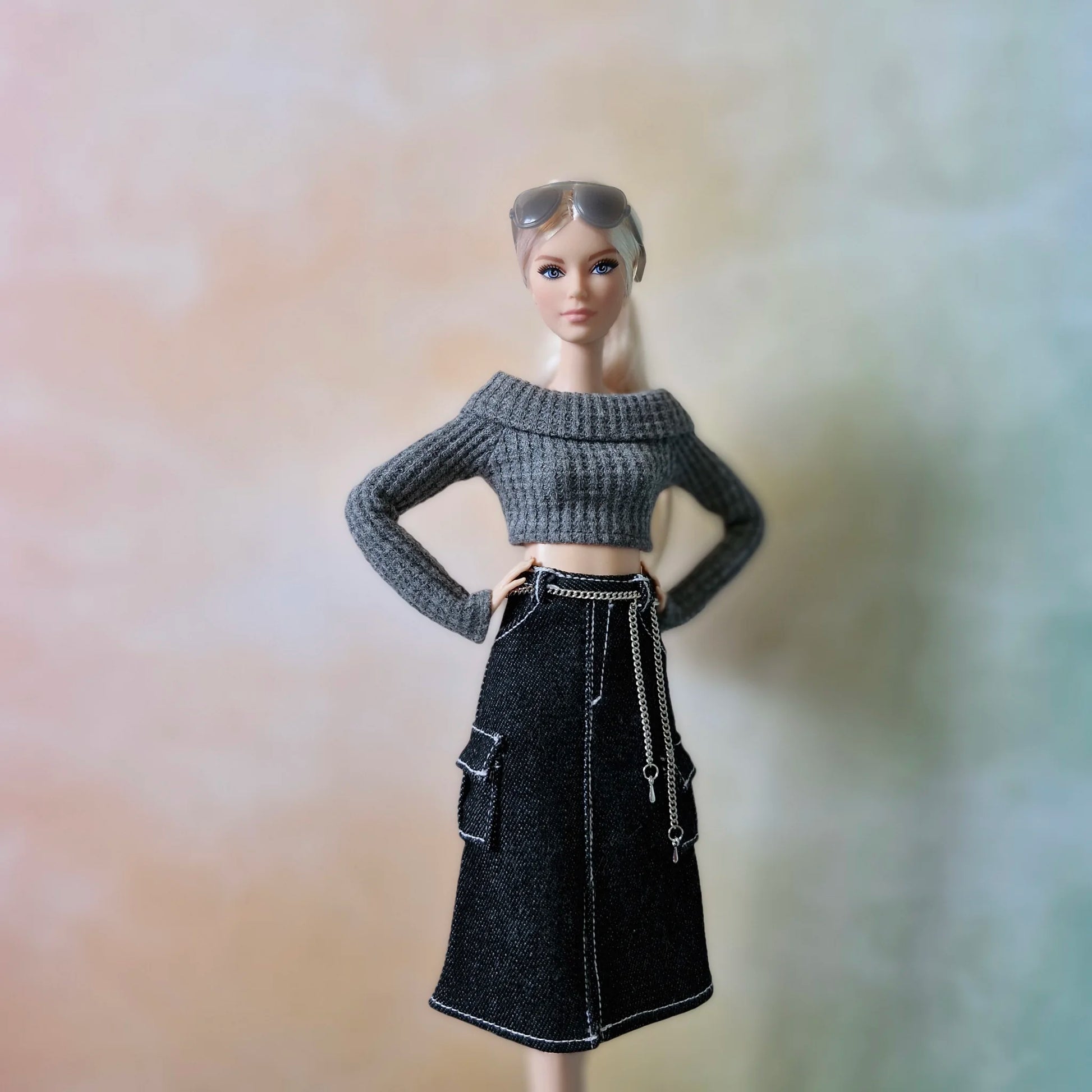 Fashion doll wearing grey off-shoulder crop top and black denim cargo midi skirt, posing with hands on hips.