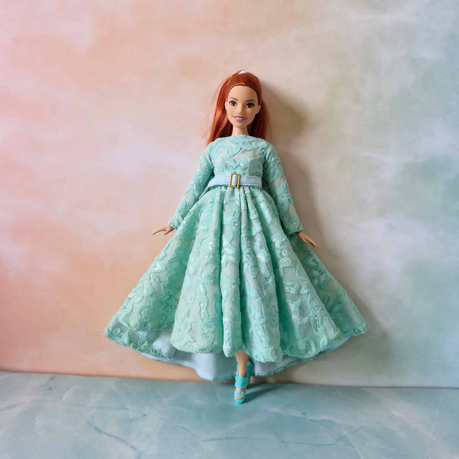 Front view of Barbie Curvy doll showcasing the elegant drape and high-low skirt of the mint green lace gown.
