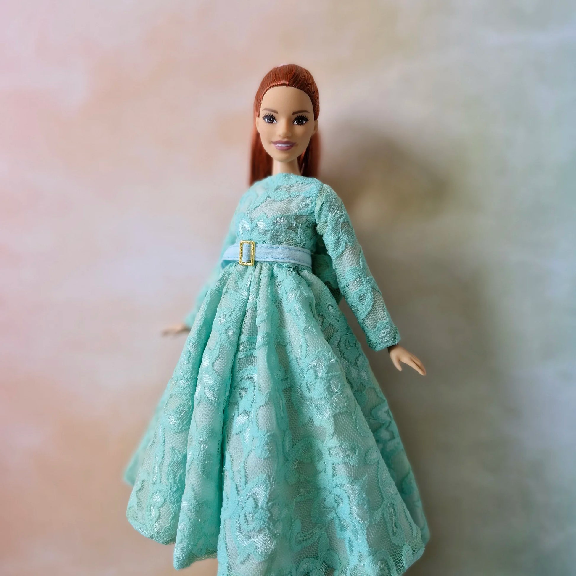 Close up torso view of Barbie Curvy doll in mint green lace dress highlighting the fabric texture and belt detail.