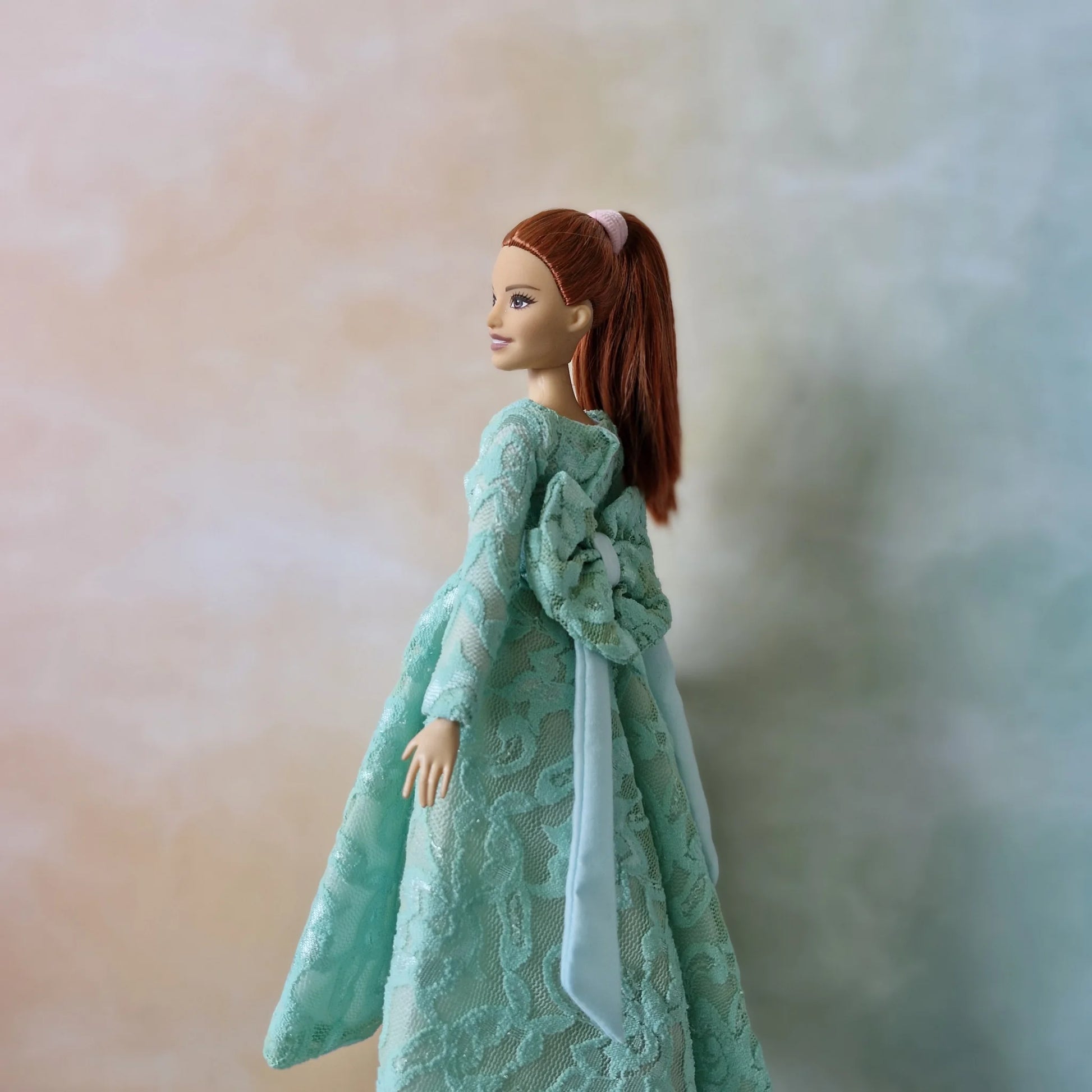 Back view of mint green lace doll dress showing large coordinating bow detail at the waist on Barbie Curvy doll.