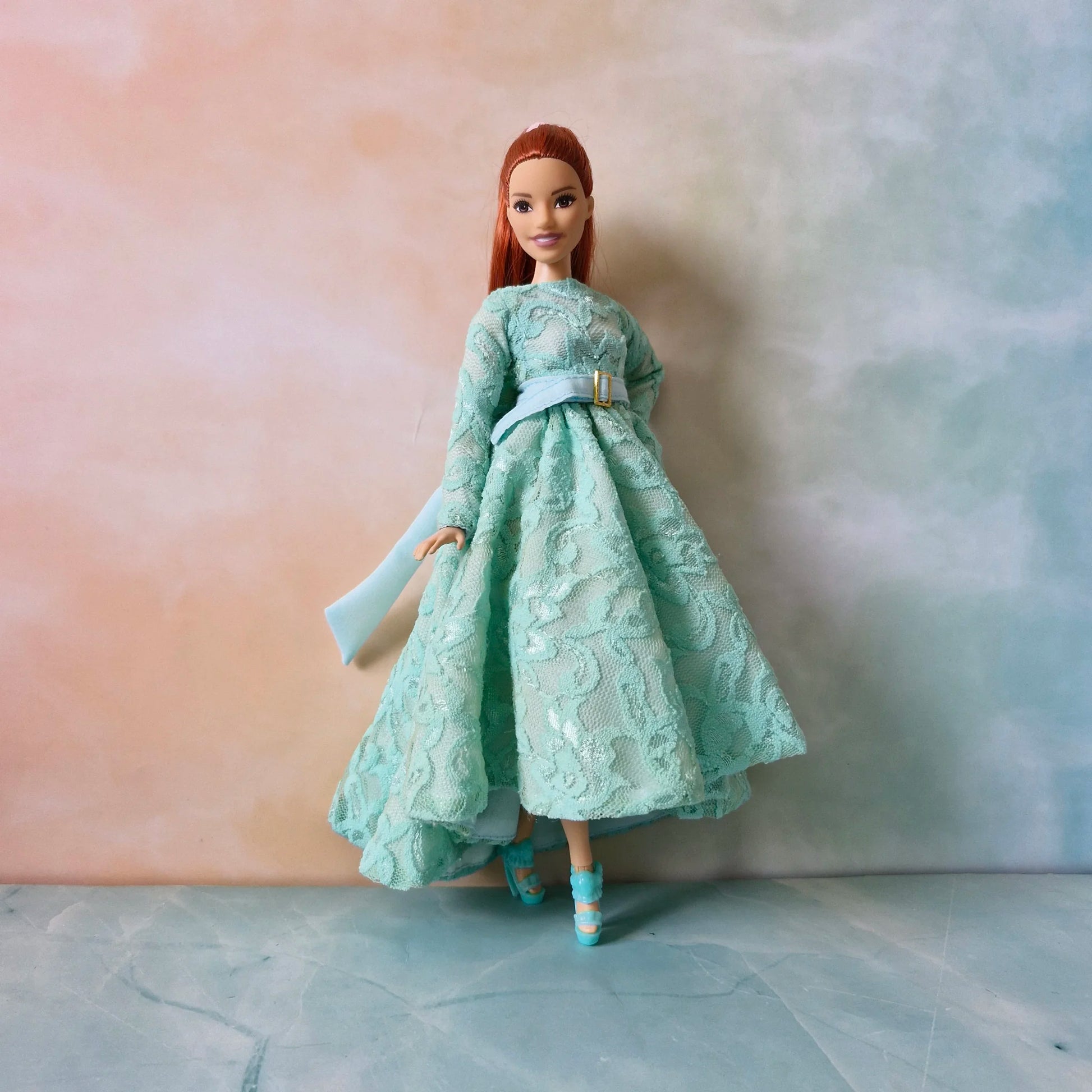 Full length view of Barbie Curvy doll modeling mint green high-low lace gown with belt and matching shoes.