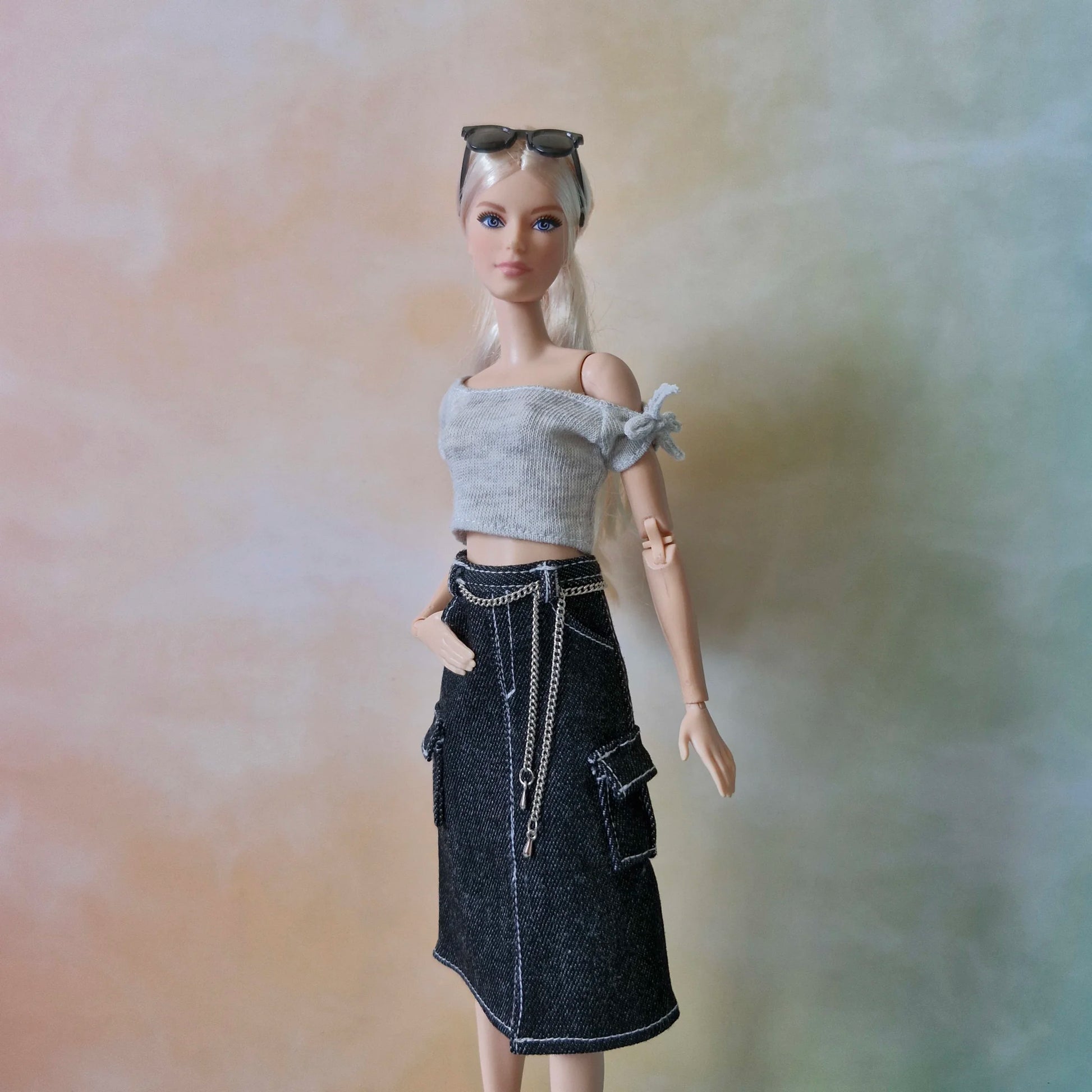 Blonde Barbie doll wearing grey crop top and black denim cargo midi skirt with chain detail