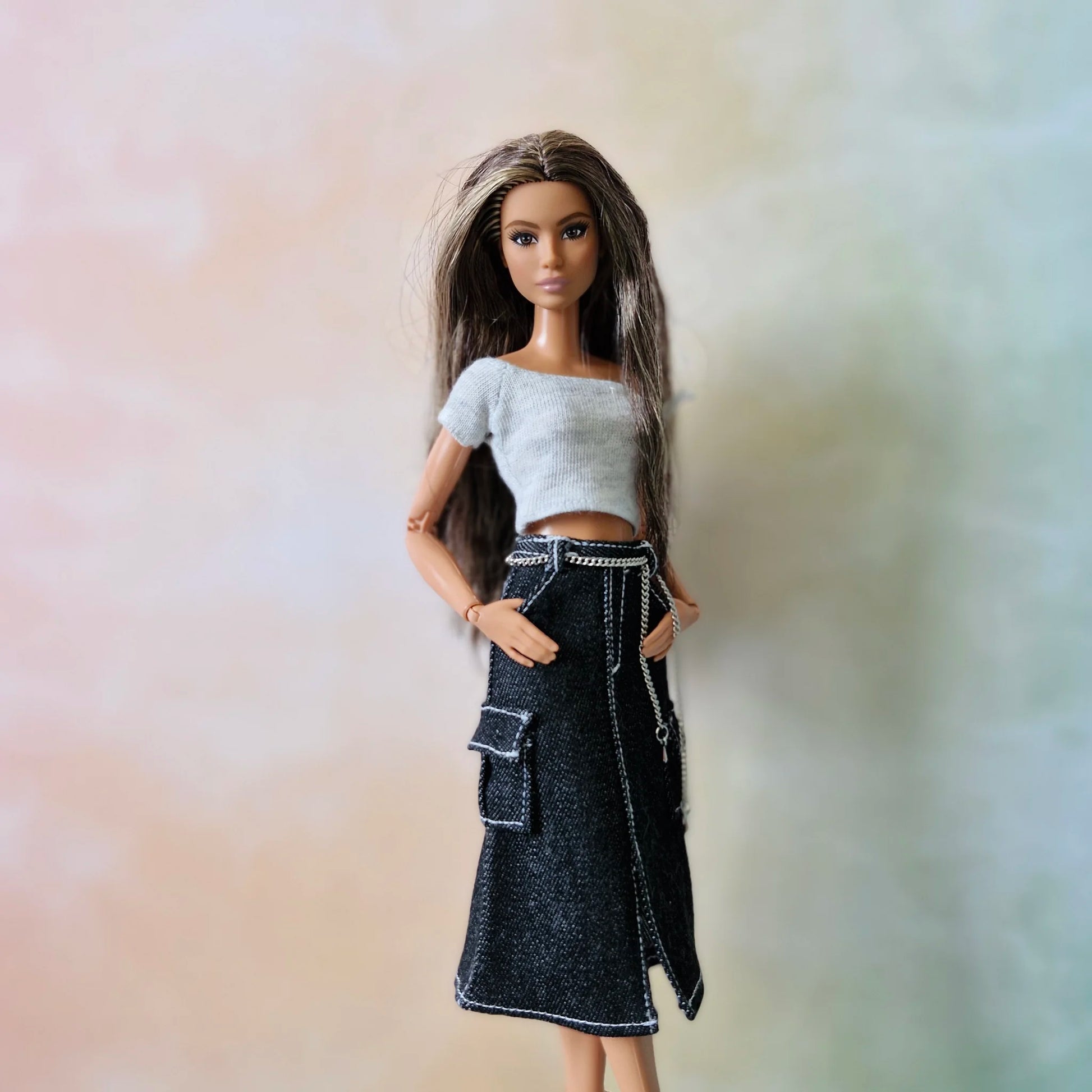 Brunette Barbie doll models white crop top and black denim cargo midi skirt with chain