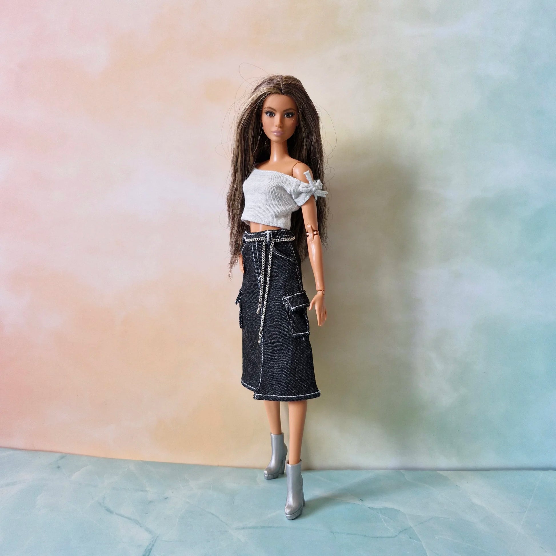 Full length brunette Barbie doll wearing white top, black denim cargo skirt, and silver boots