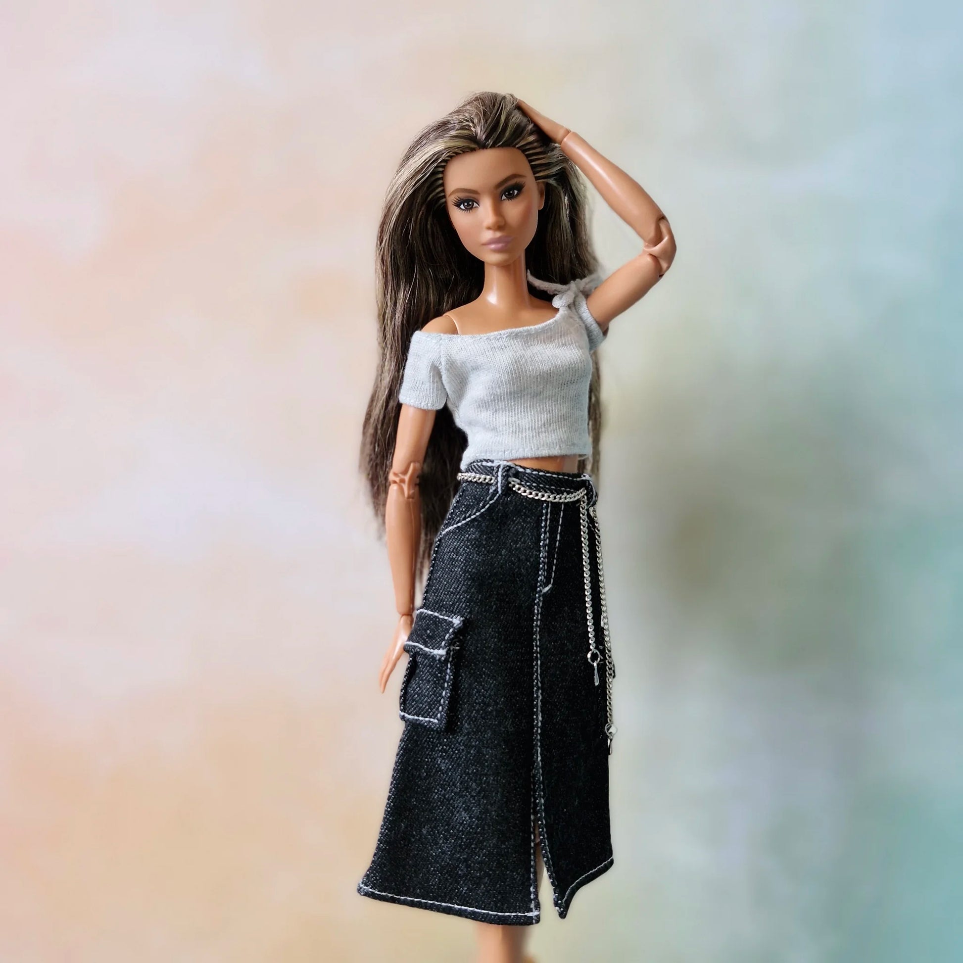 Blonde Barbie doll models black denim cargo skirt and grey top with hands in pockets
