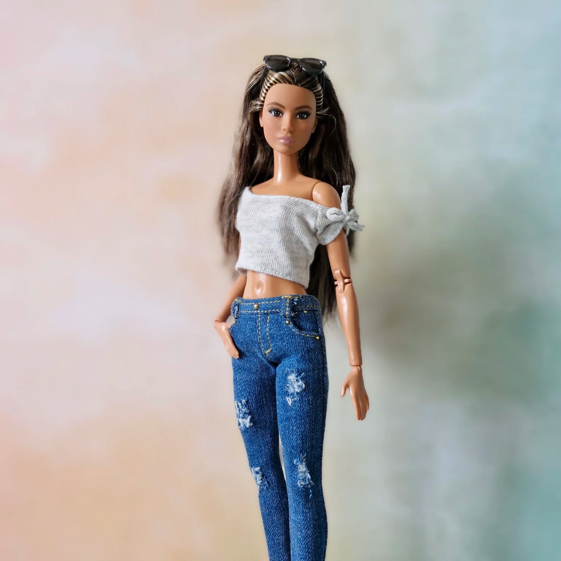 Brunette Barbie doll models ripped blue jeans and white top with hands in pockets and sunglasses
