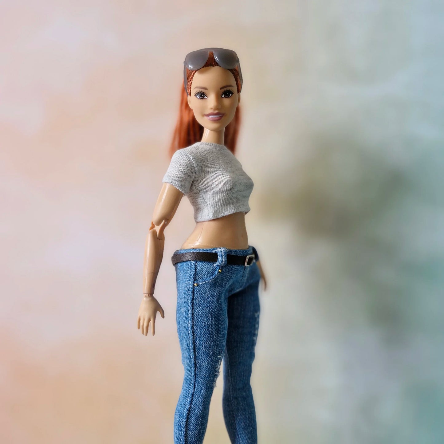 Close up redhead Barbie doll in grey crop top and ripped blue jeans with belt detail