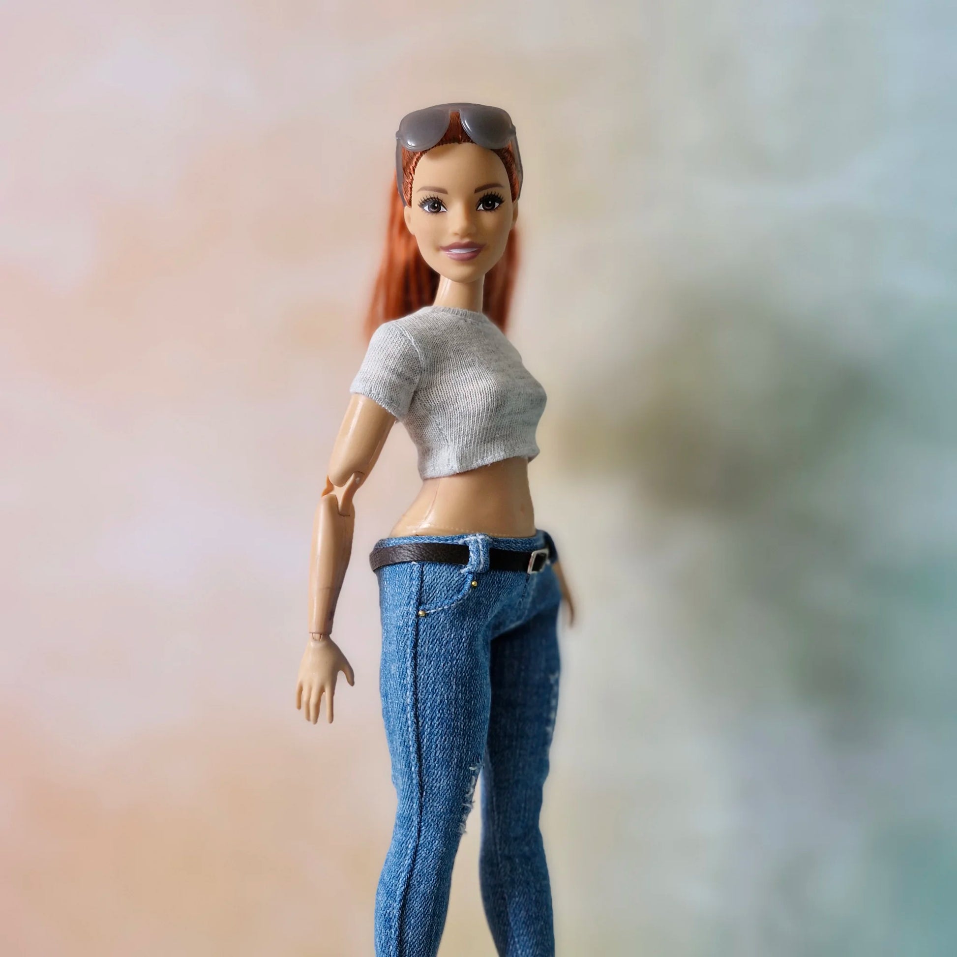 Close up redhead Barbie doll in grey crop top and ripped blue jeans with belt detail
