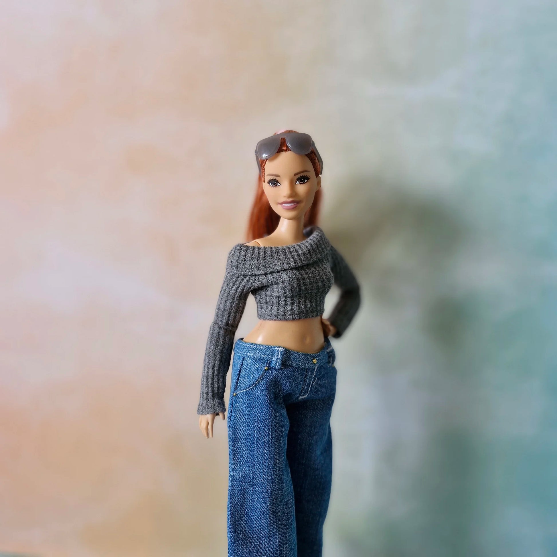 Redhead Curvy Barbie doll wearing grey off-shoulder crop top and wide-leg denim jeans, hand on hip