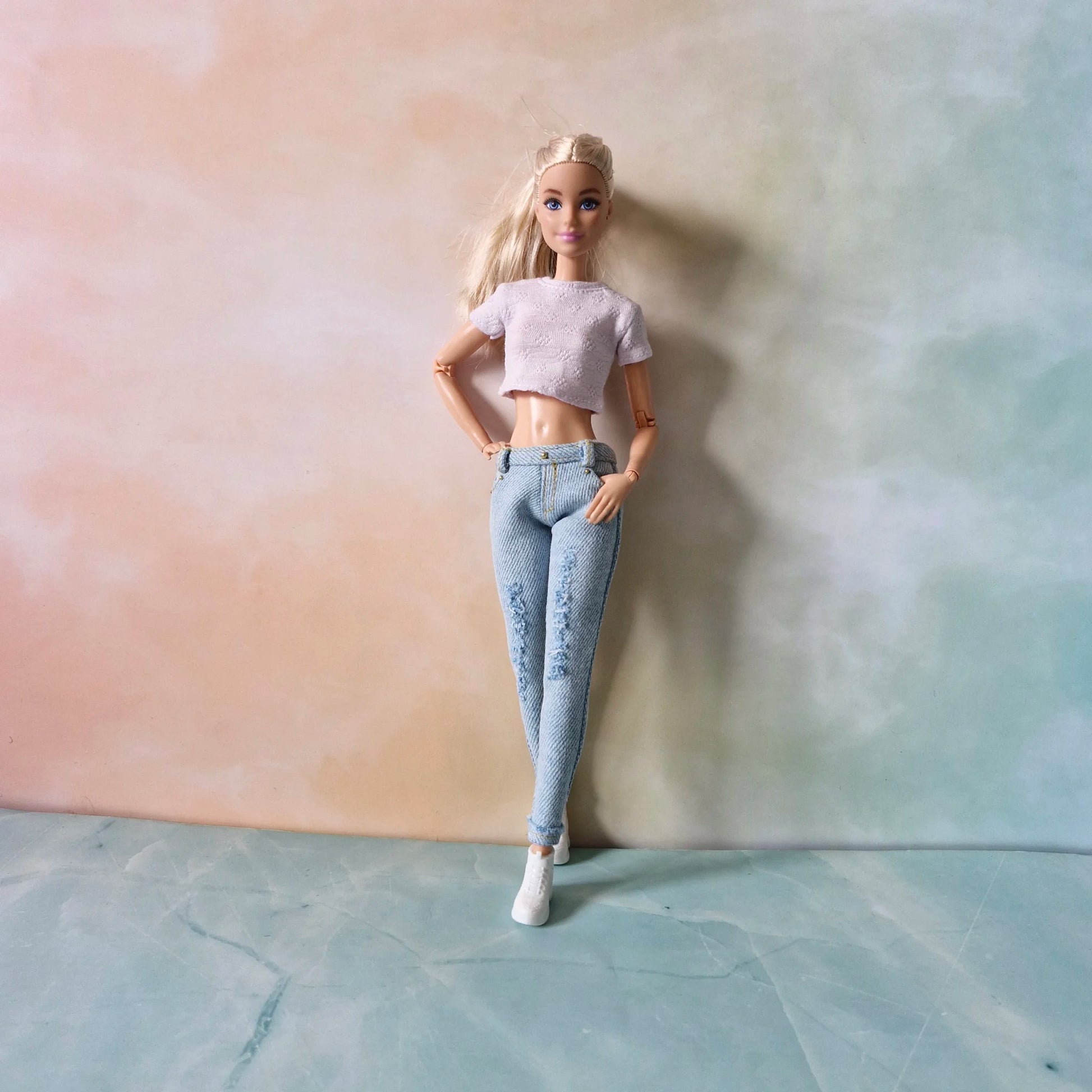 Full length blonde Barbie doll wearing white crop top and light blue ripped jeans with hand in pocket