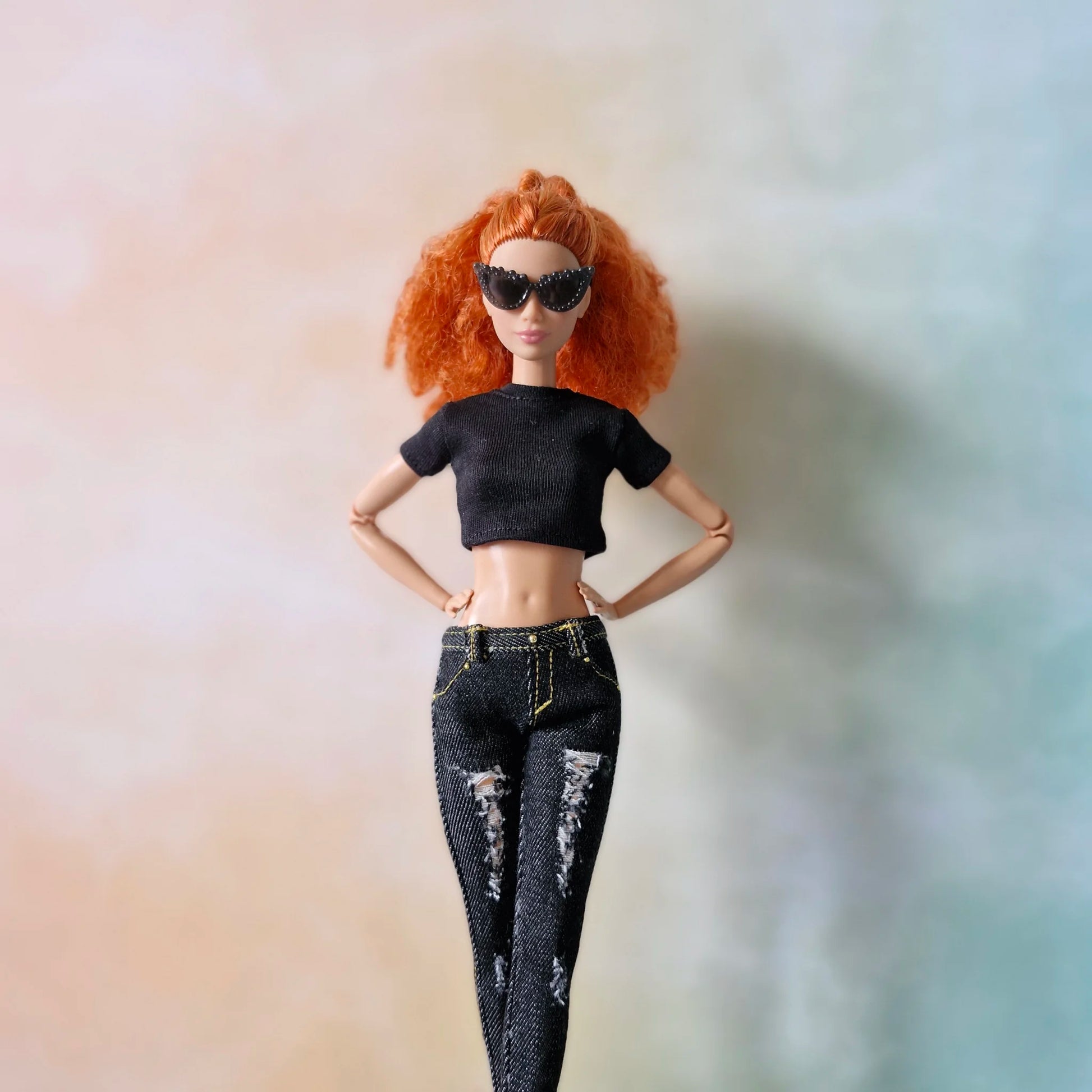 Redhead Barbie doll wearing black crop top and black distressed skinny jeans with hands on hips