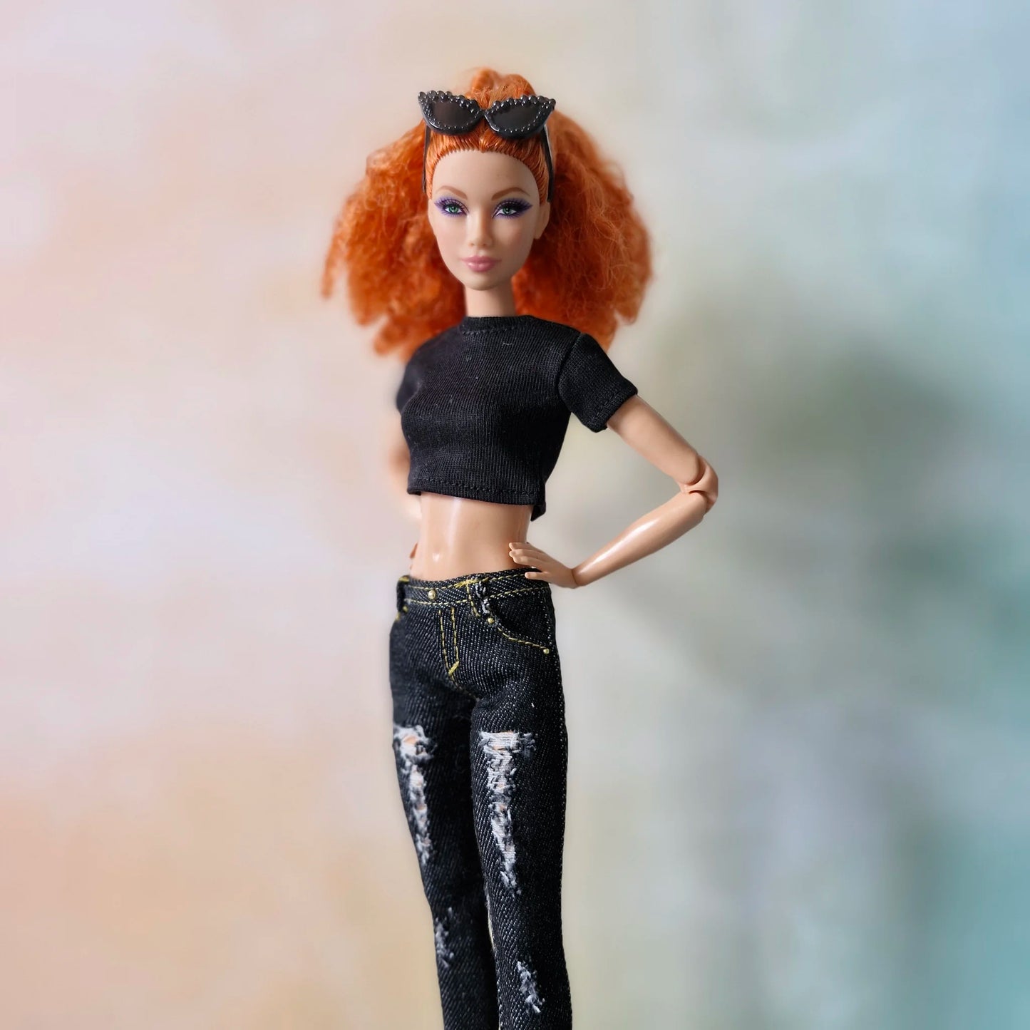 Redhead Barbie doll poses in black crop top and ripped black skinny jeans with hand on hip