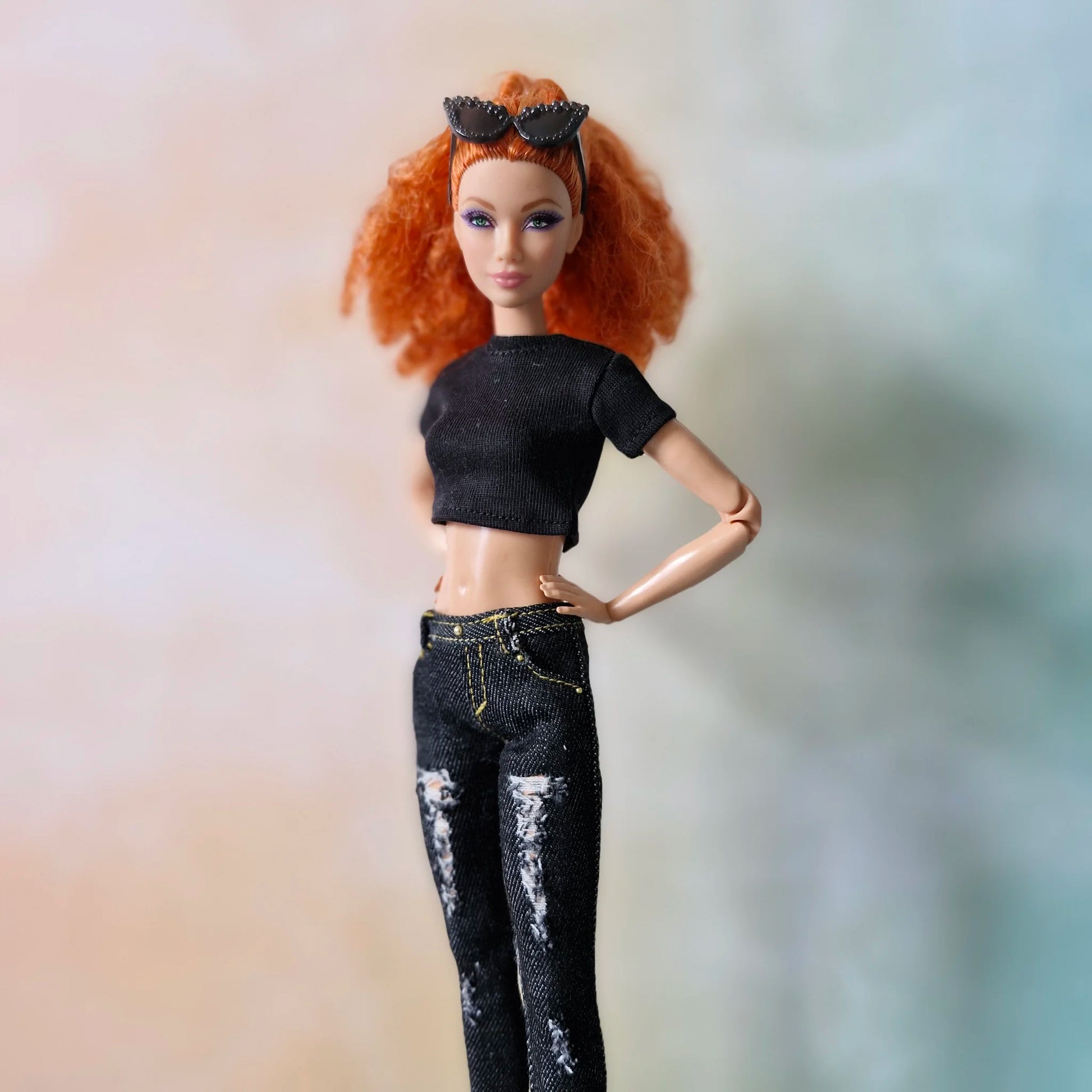 Redhead Barbie doll poses in black crop top and ripped black skinny jeans with hand on hip