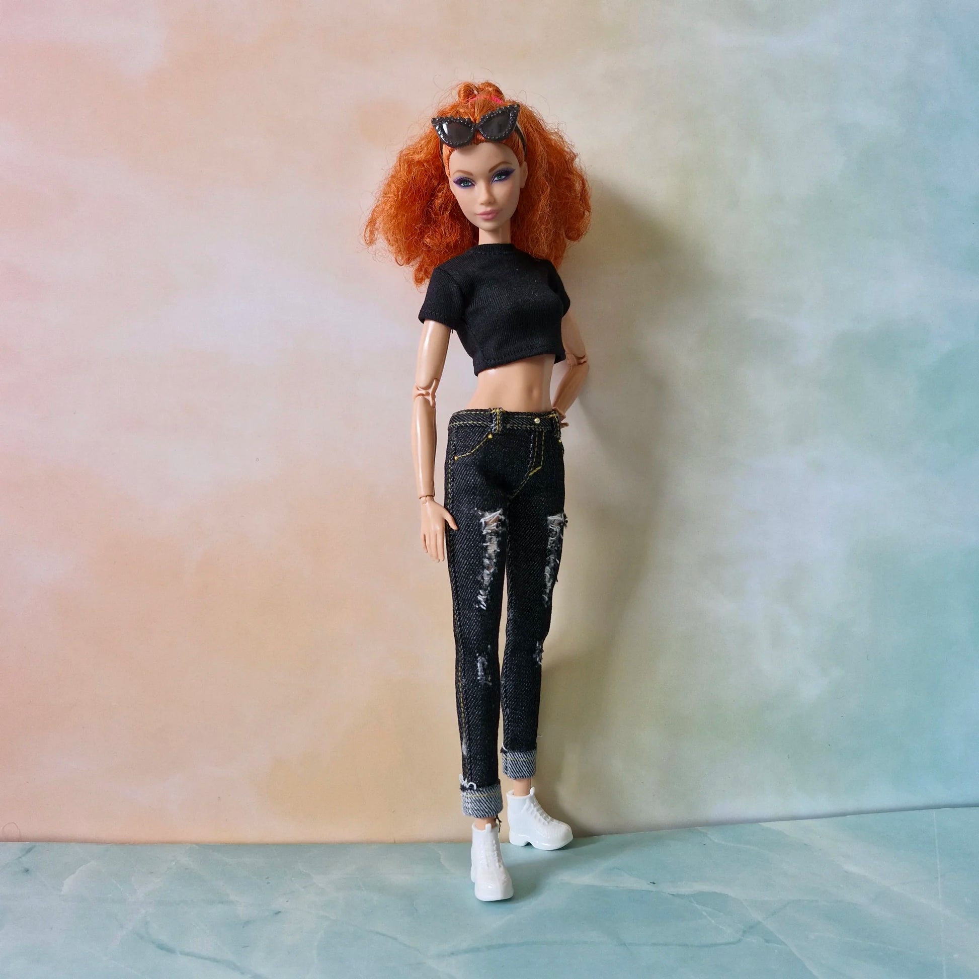 Full length redhead Barbie doll modeling black crop top and distressed black jeans with rolled cuffs