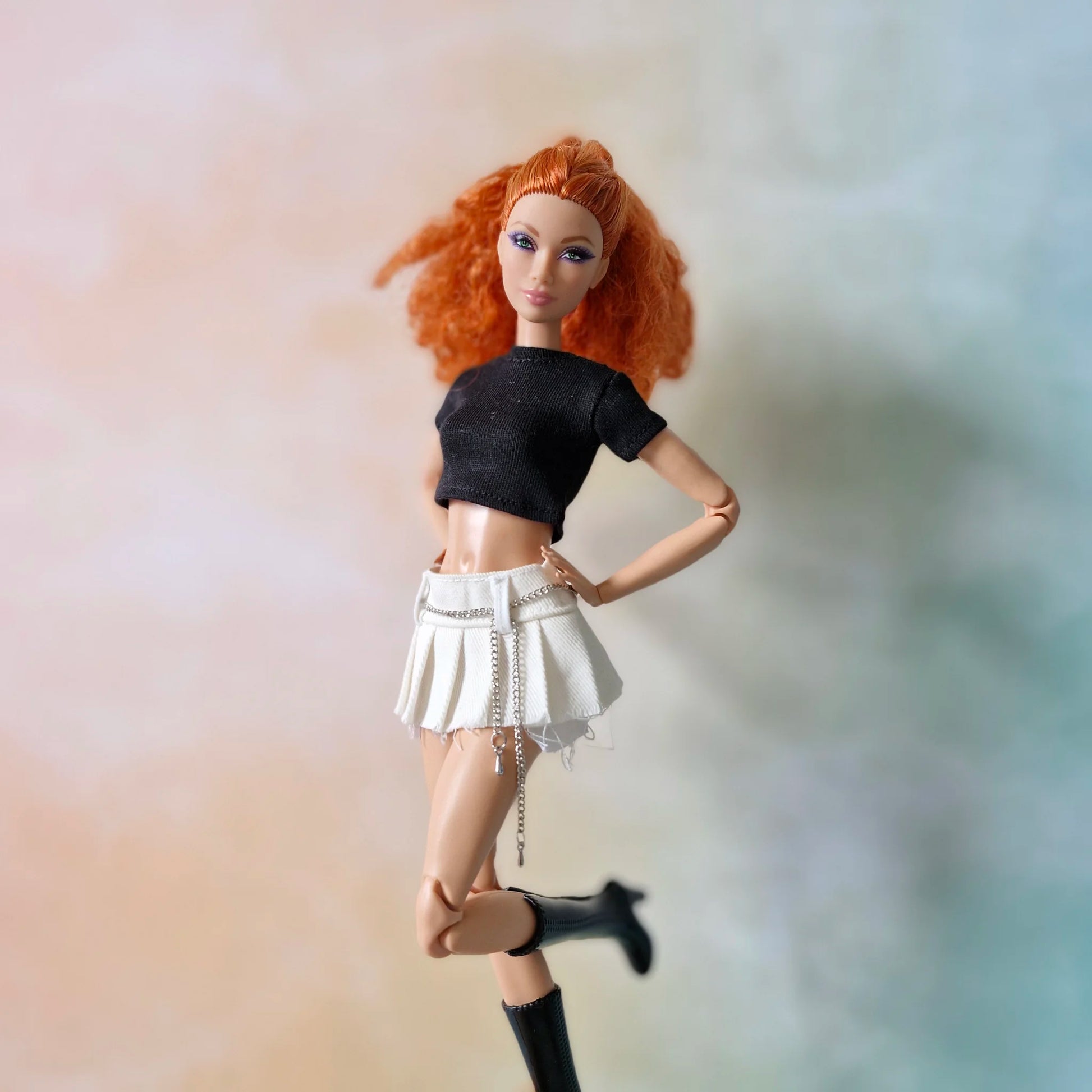 Redhead doll in black top and white pleated chain skirt kicking leg up