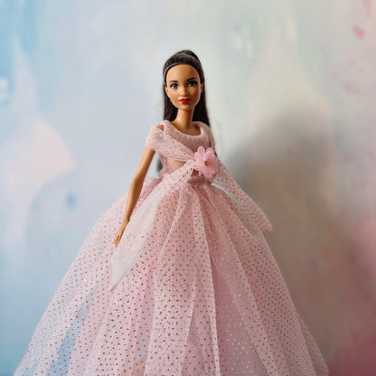Close-up front view of Barbie doll in glamorous pink glitter tulle dress with flower.