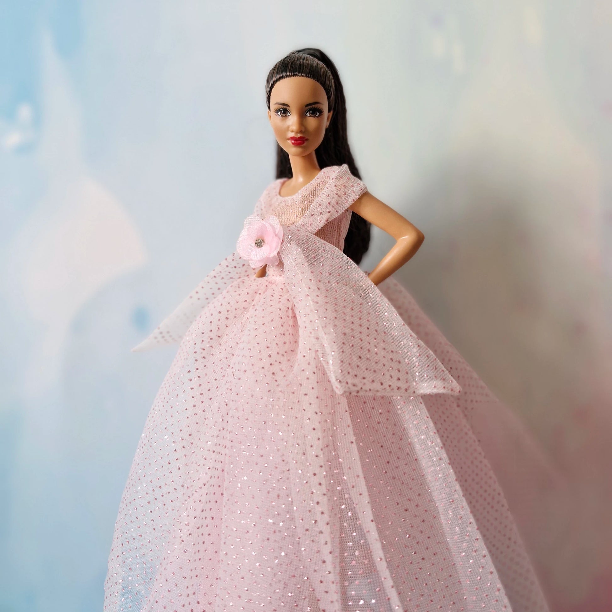 Side angle view of Barbie doll elegant in pink sparkly floor-length tulle gown.