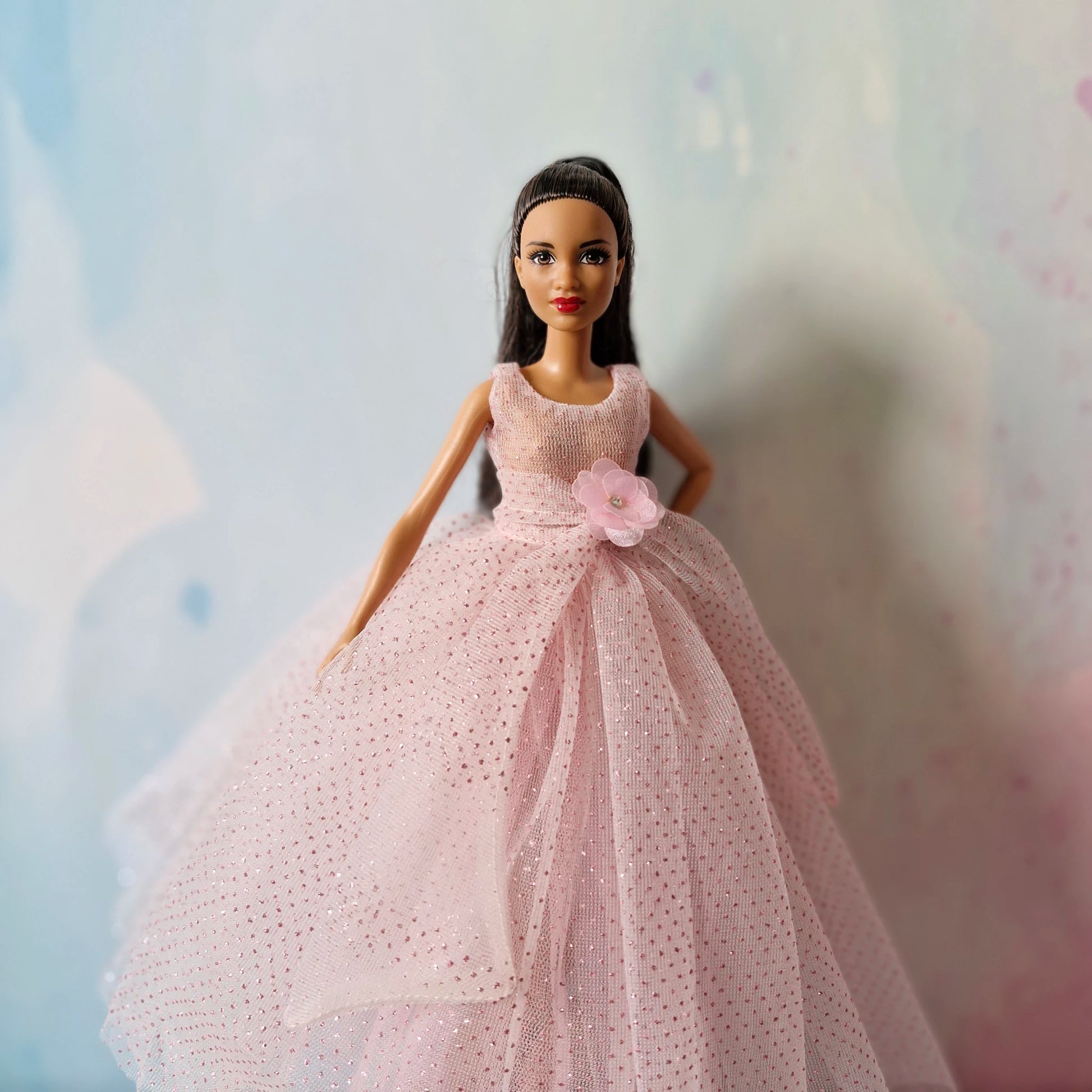 Barbie doll modeling pink sparkly tulle gown, slight angle view showing bodice detail.