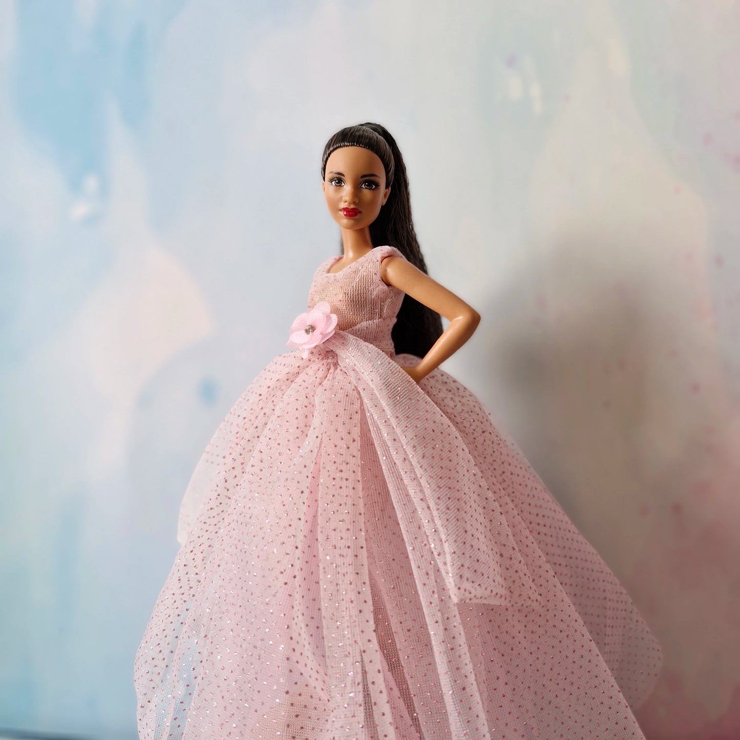 Barbie doll close-up wearing elegant pink sparkly tulle ball gown with flower accent.