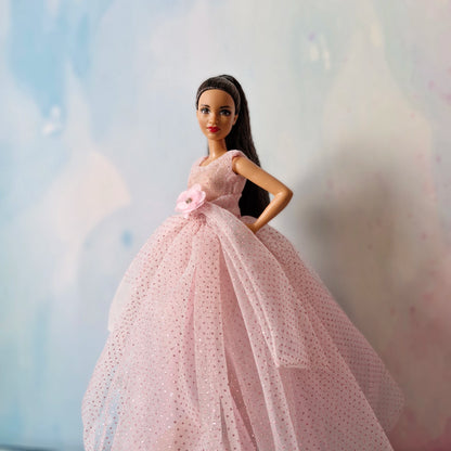 Barbie doll close-up wearing elegant pink sparkly tulle ball gown with flower accent.