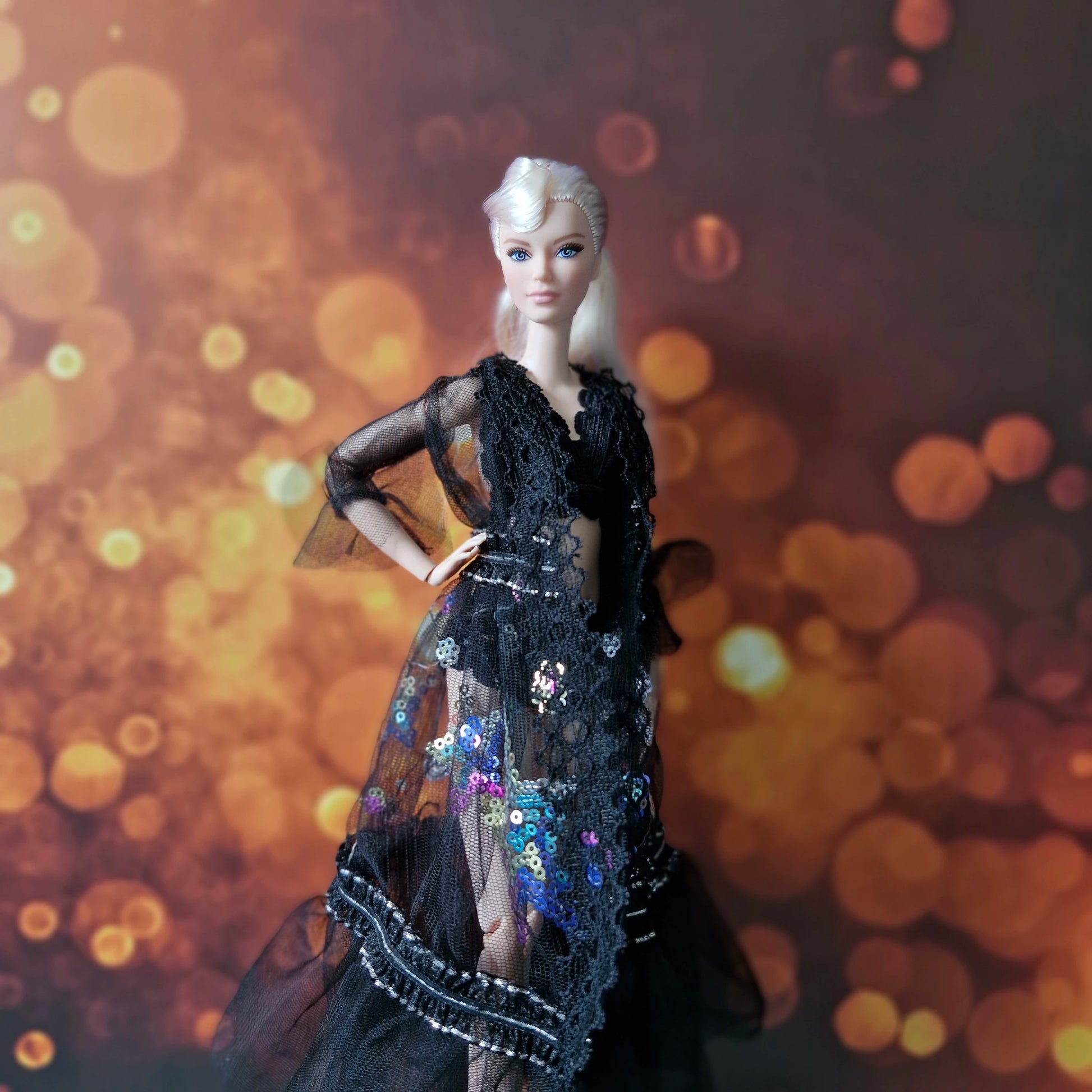 Side profile of blonde Barbie doll in glamorous black sheer lace and sequin overlay gown.