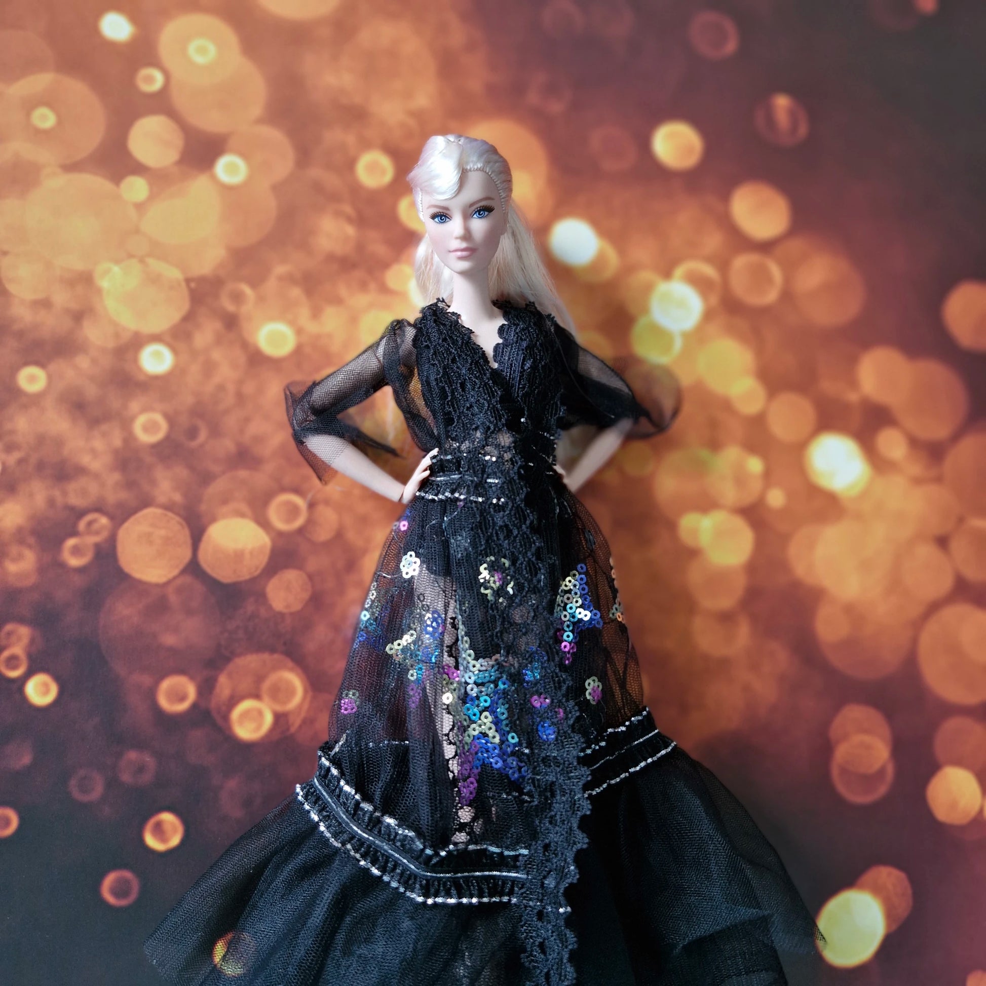 Front view of blonde Barbie doll in dramatic black sheer lace and sequin evening gown.