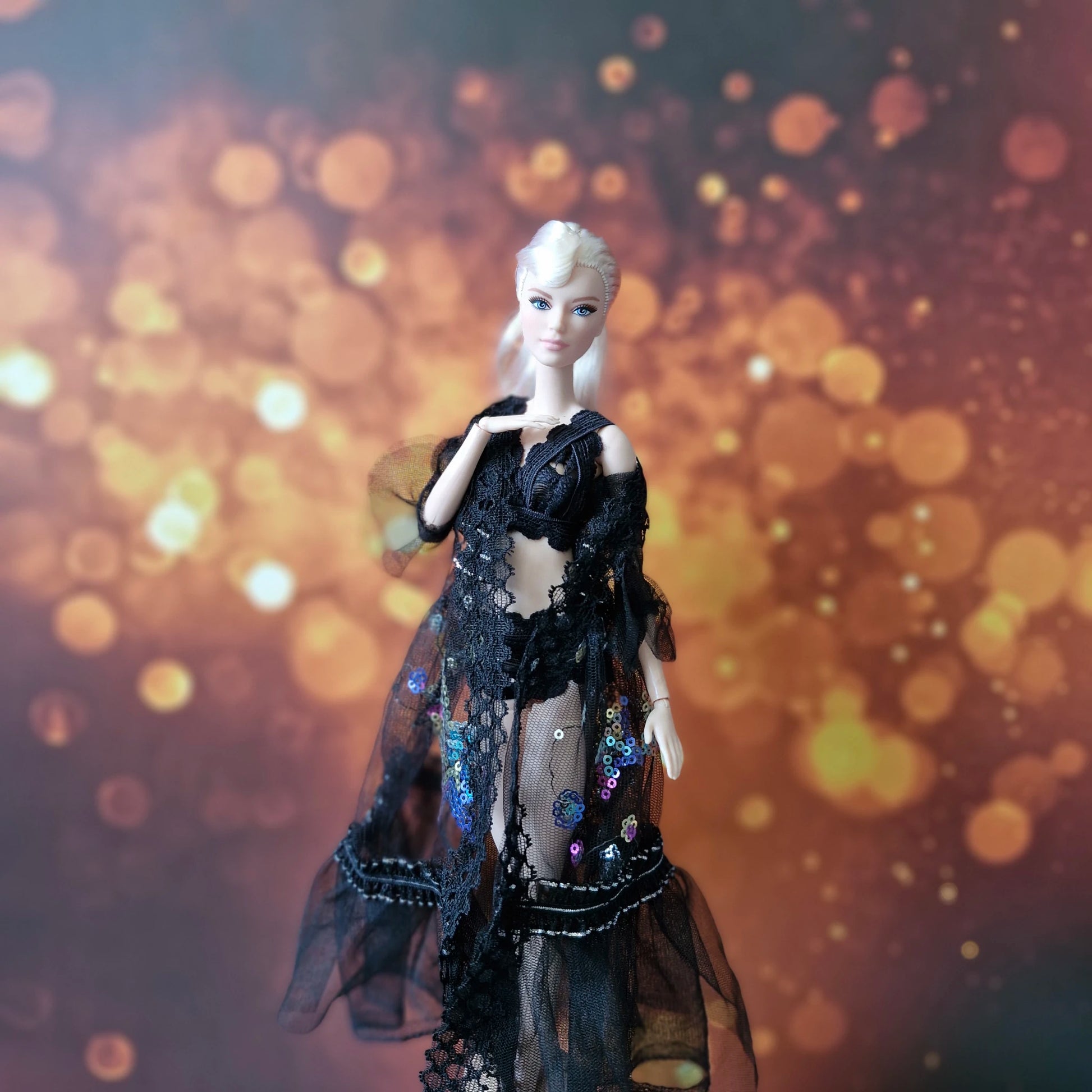 Close-up of blonde Barbie in black lace and sequin sheer overlay gown, elegant pose.