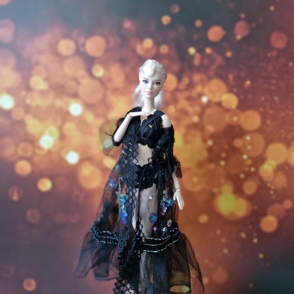 Close-up of blonde Barbie in black lace and sequin sheer overlay gown, elegant pose.
