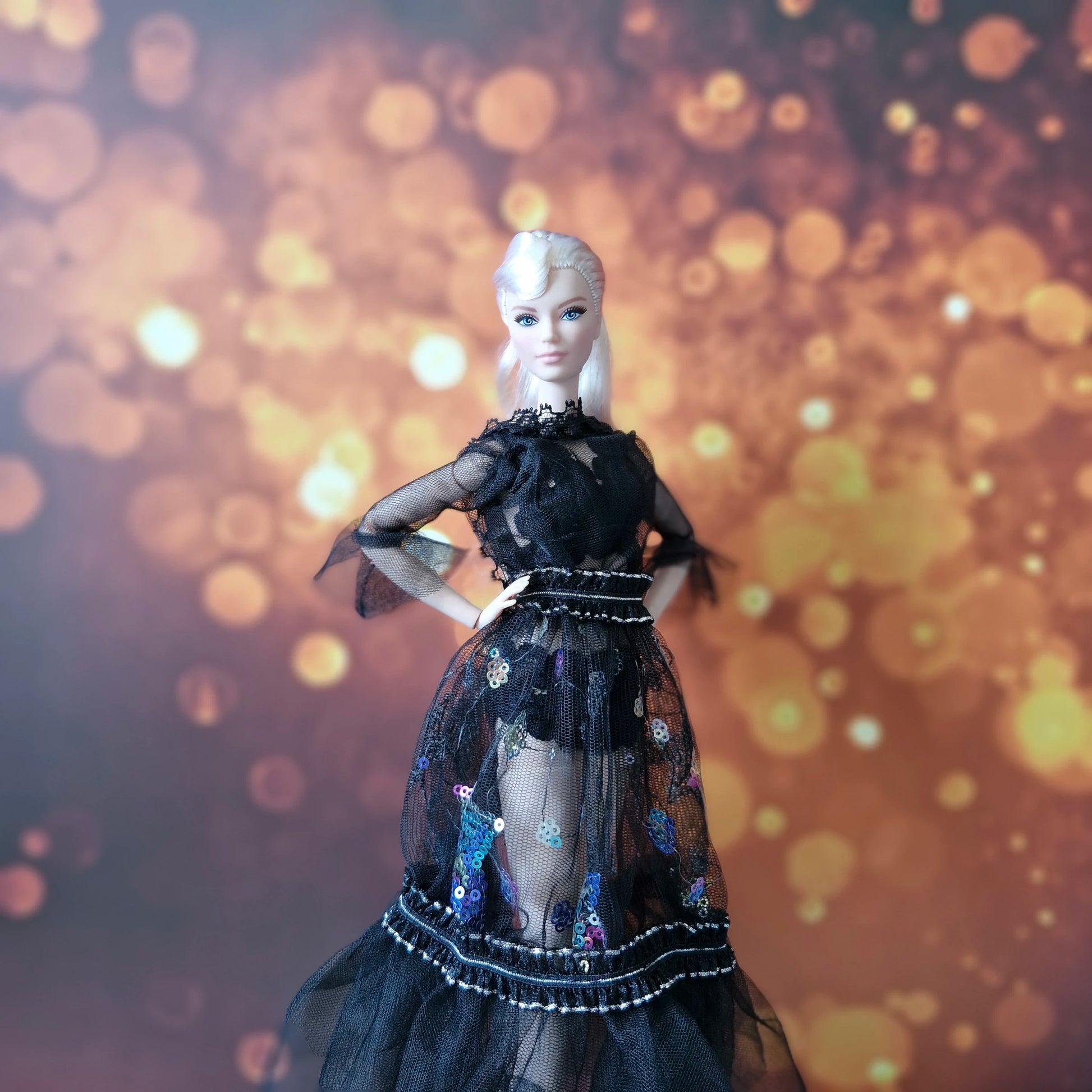 Blonde Barbie posing confidently in black sheer lace gown with vibrant sequin accents.